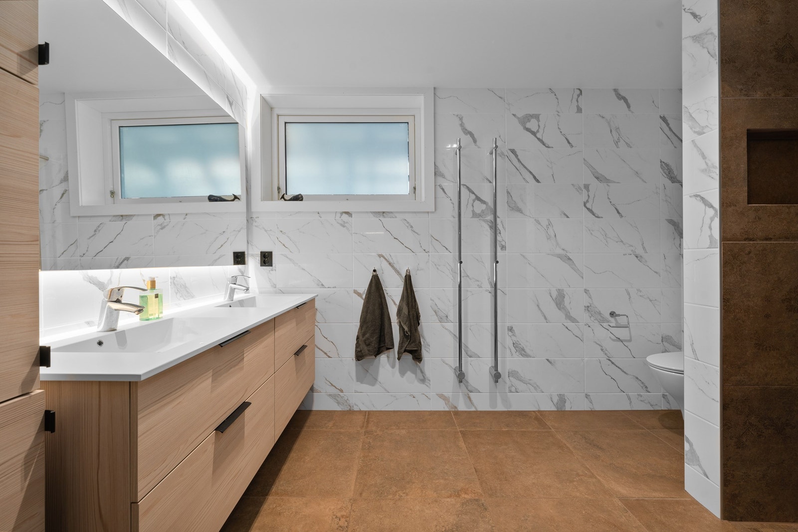 Bad i underetasje. Romslig og pent bad med varmekabler i gulv. Praktiske håndklevarmere montert på vegg. Galleribilde