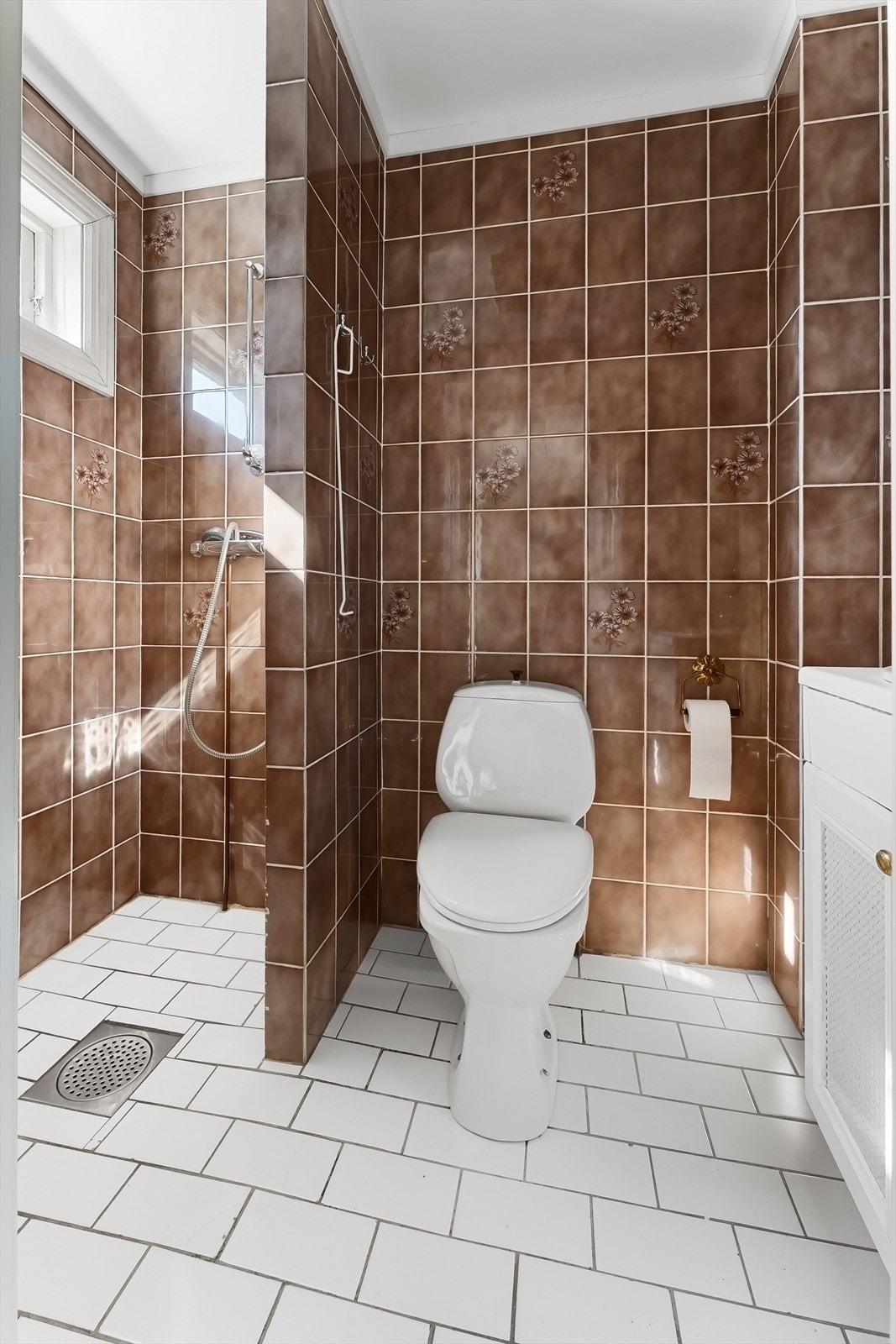 Innredning med servant og speil på vegg, gulvmontert WC og åpen dusjnisje. Galleribilde