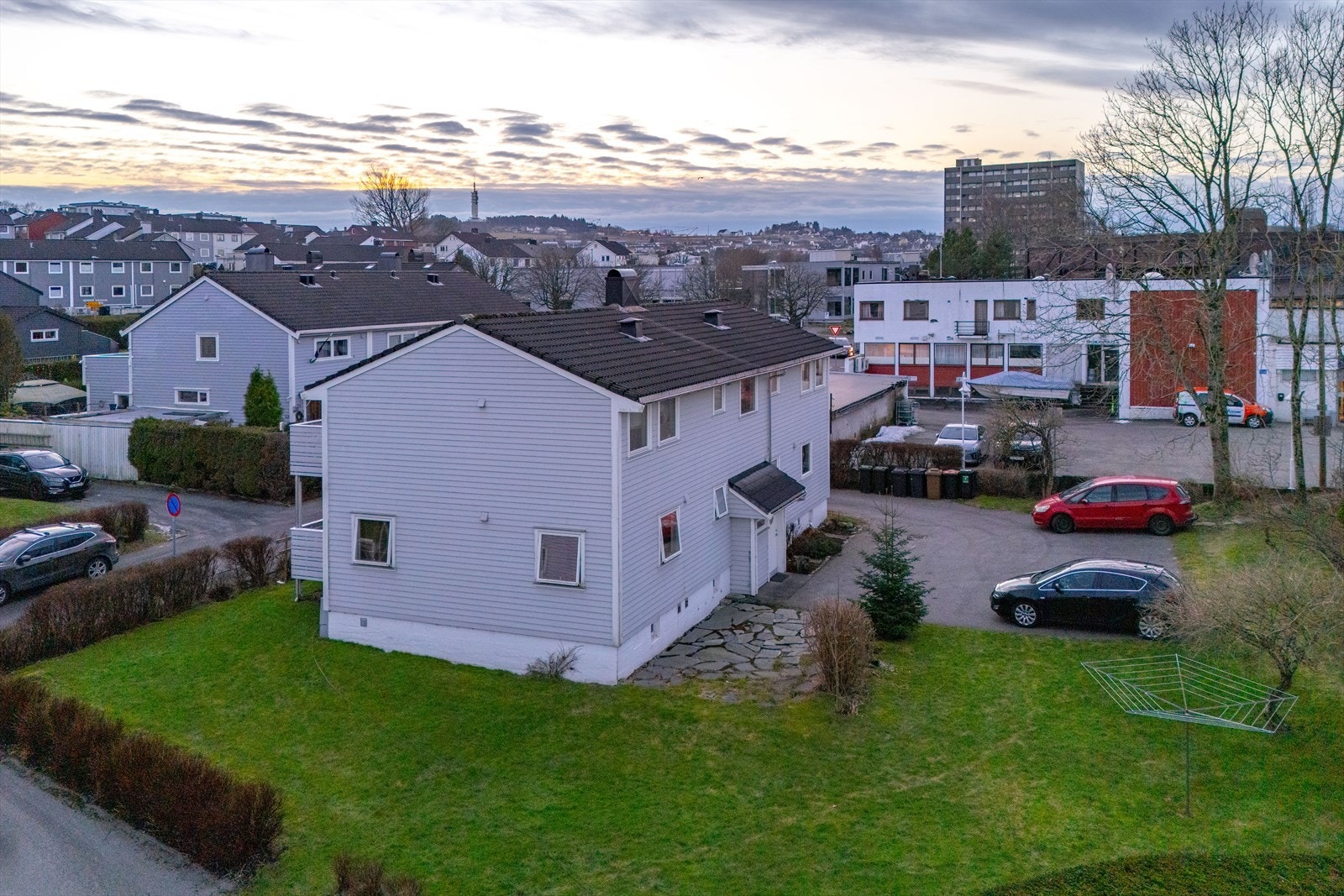 Stemveien 6 ligger fint til på en stor felles tomt med gressplen, busker og trær Galleribilde