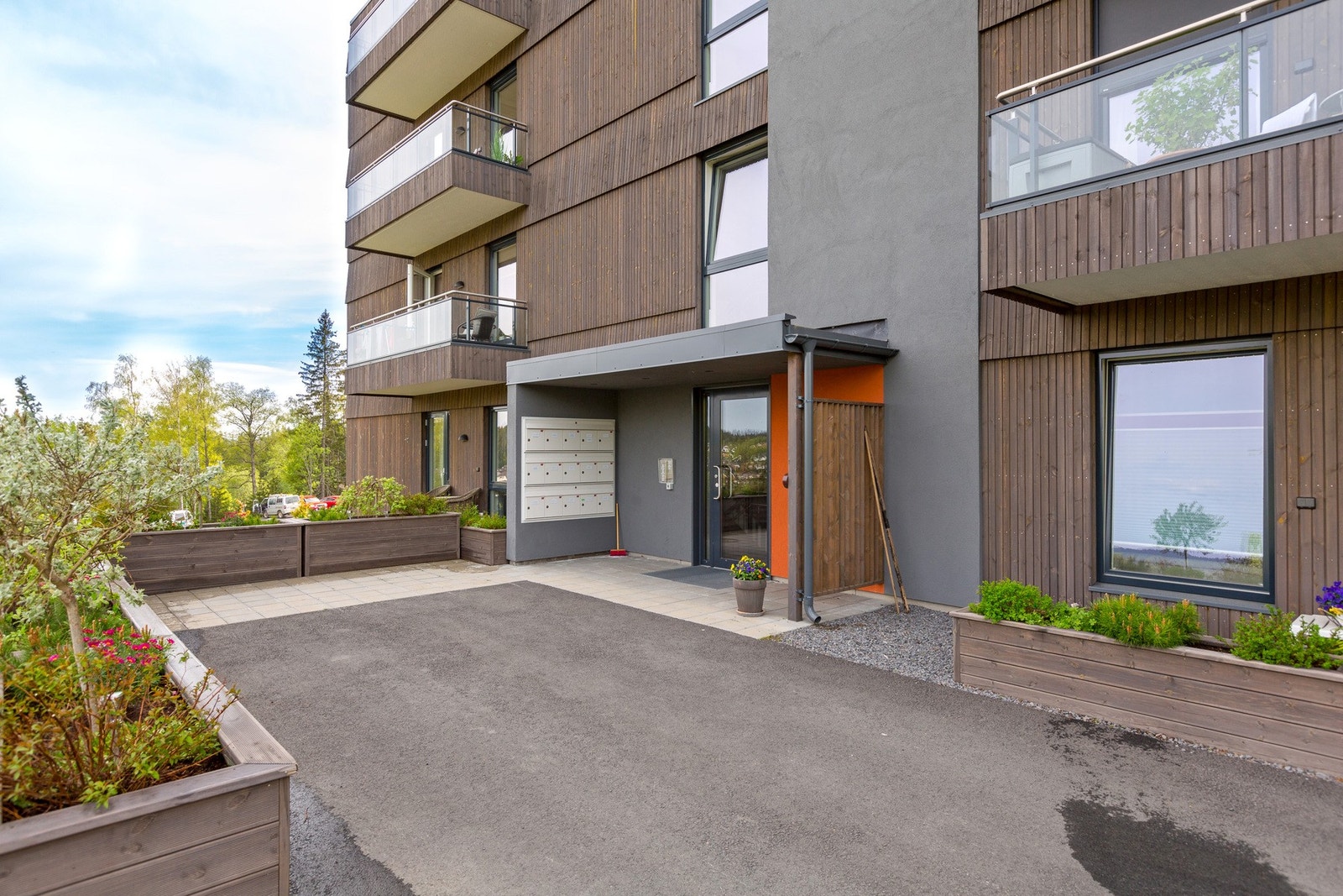 Pent inngangsparti med asfalterte gangarealer. Felles postkassestativ ved inngangspartiet. Galleribilde