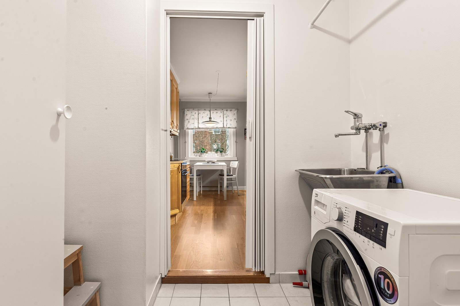 Vaskerommet har flislagt gulv, opplegg for vaskemaskin og utslagskum. Galleribilde