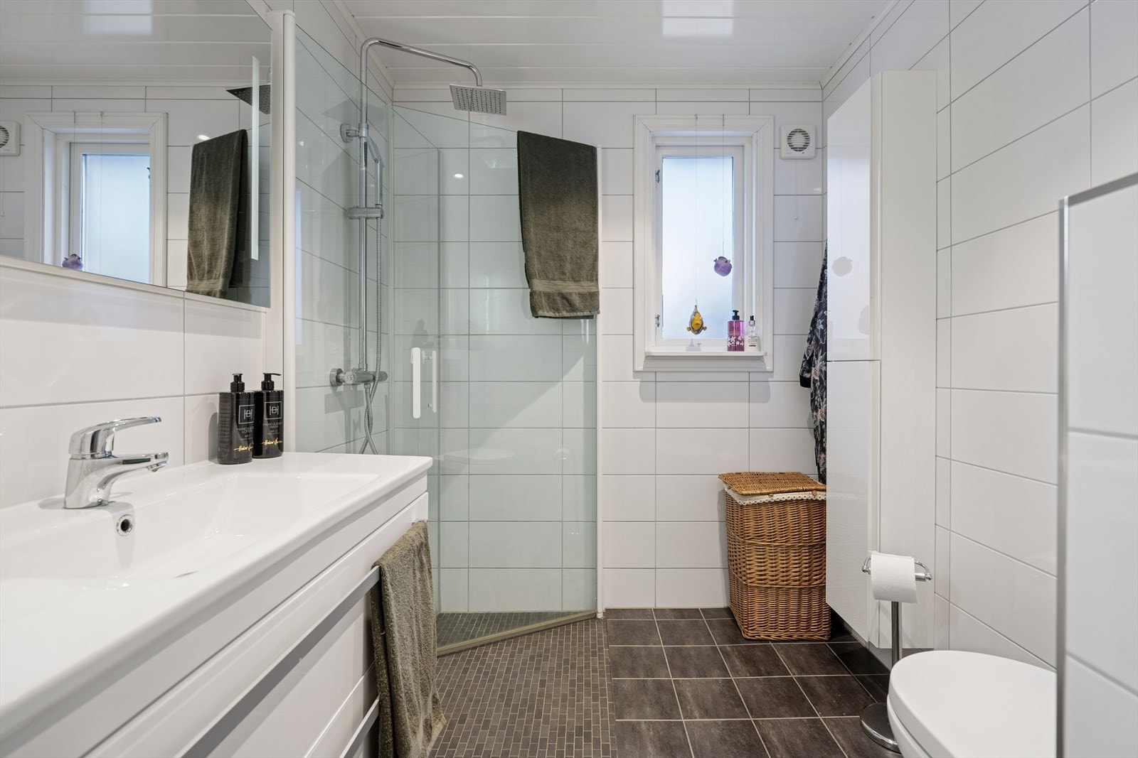 Badet i første etasje ble oppgradert i 2015 og har fliser på vegger og gulv med varmekabler. Det er innredet med heldekkende servant, moderne baderomsinnredning, dusjhjørne og vegghengt toalett. Ventilasjon skjer via elektrisk vifte på yttervegg. Galleribilde