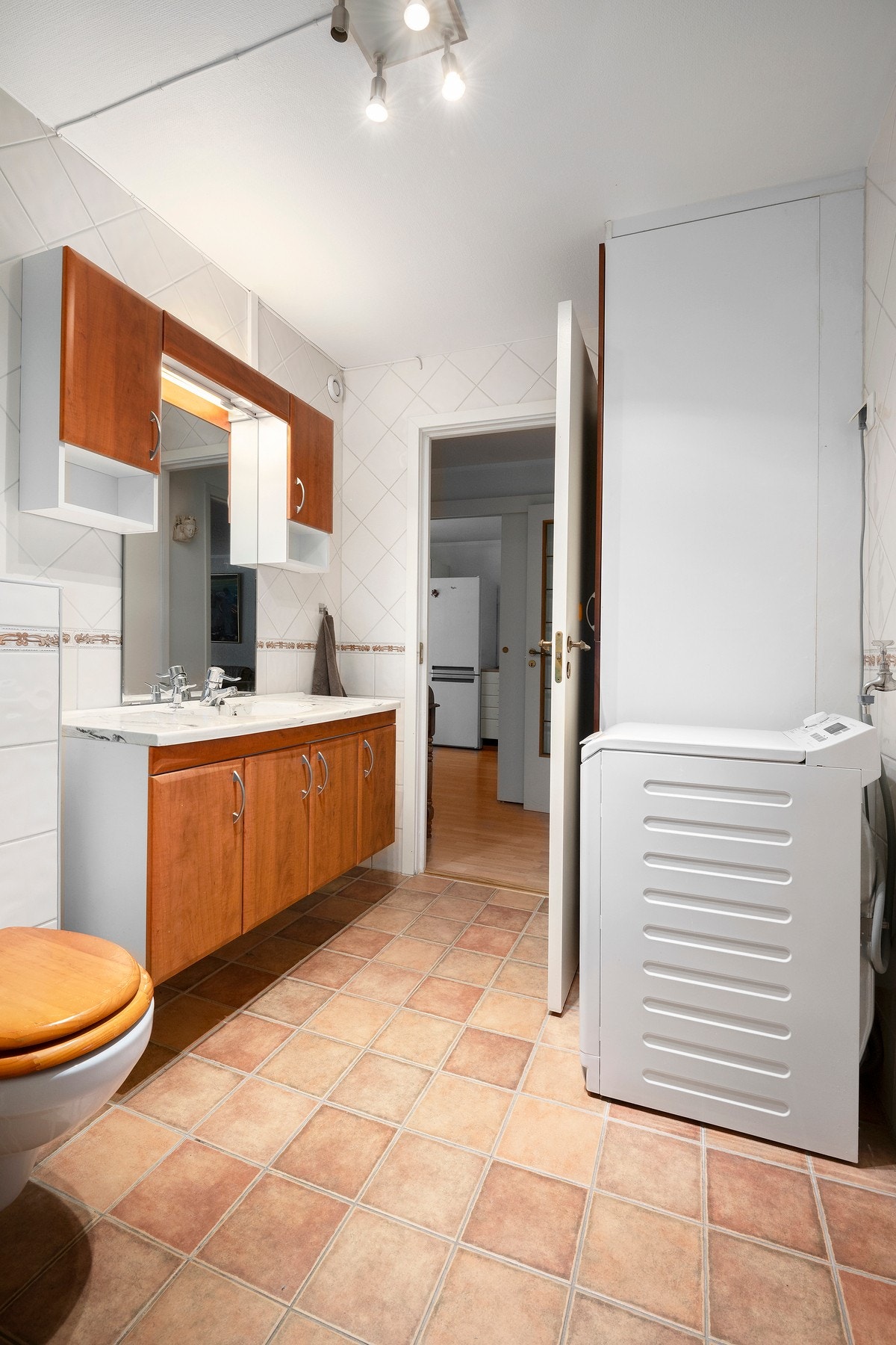 Baderom bestående av servant med underskap, toalett, dusjhjørne og opplegg vaskemaskin. Galleribilde