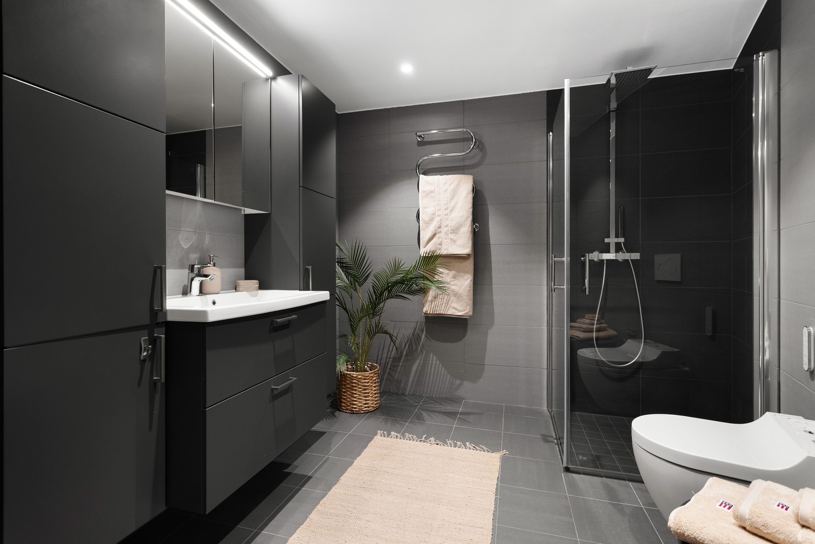 Stort hovedbad som inneholder dusjsone, servant med innredning og spyletoalett. Galleribilde