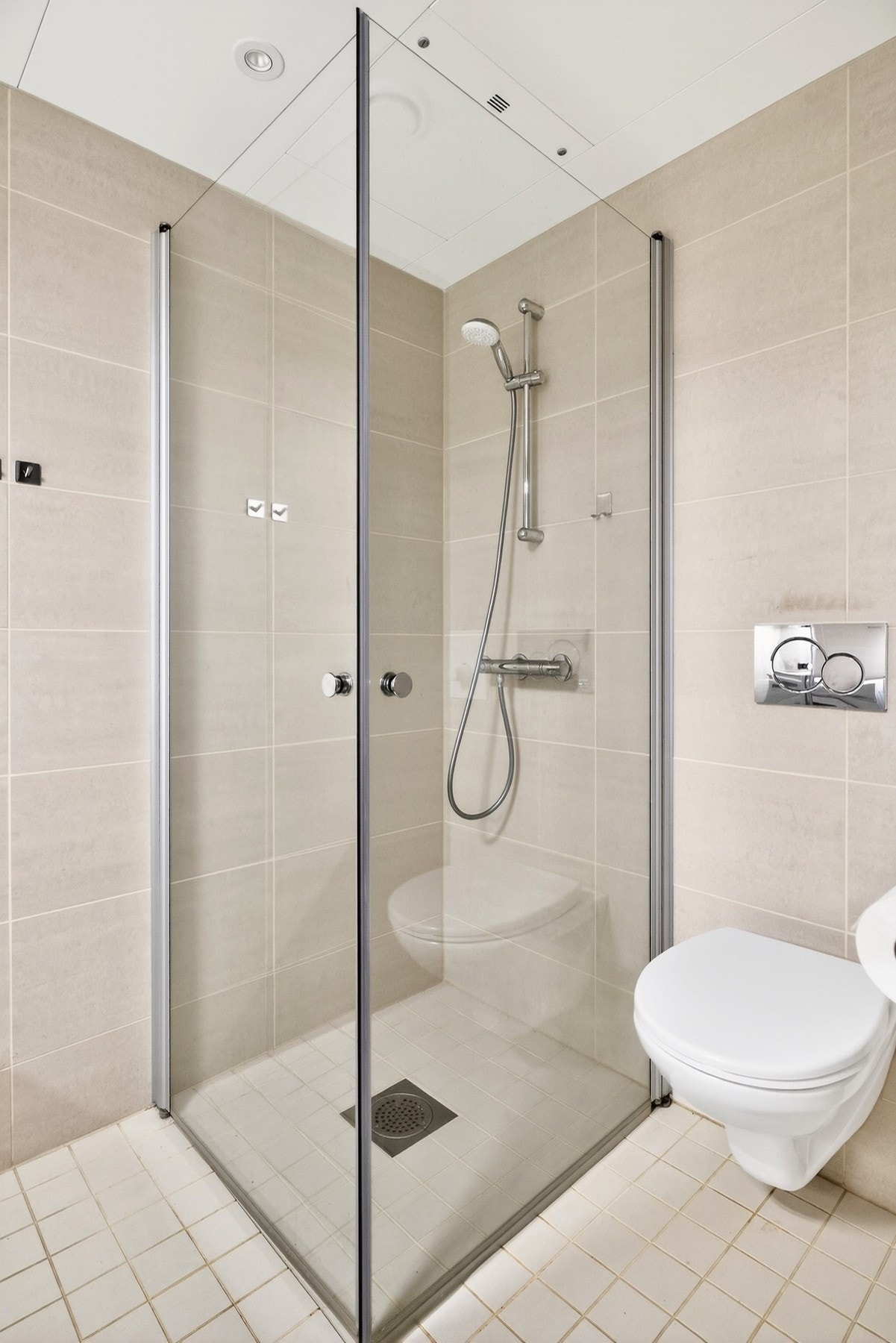 Vegghengt toalett og dusjhjørne med glassdører. Galleribilde