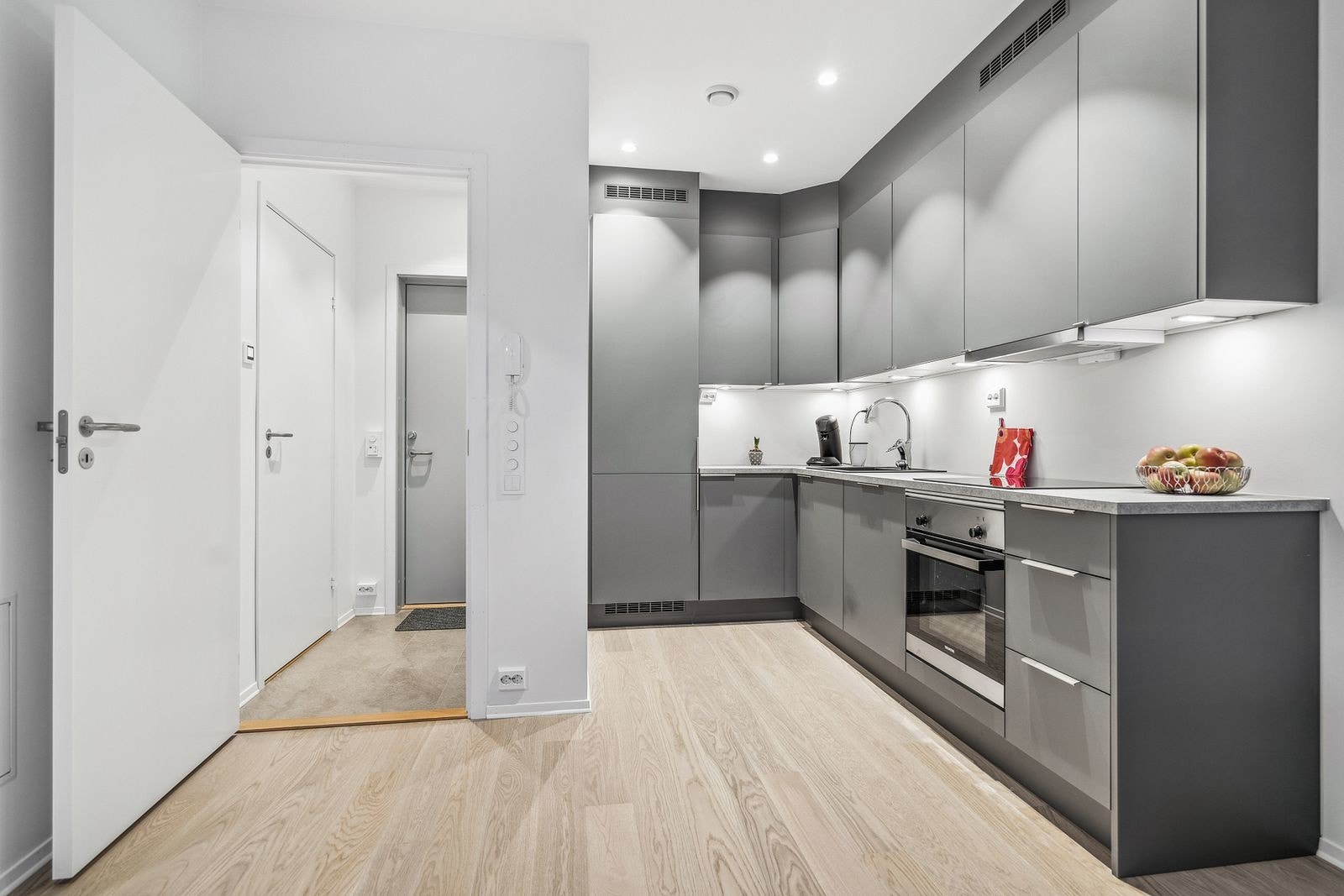 Nymotens kjøkken i delikate mørke farger, med integrerte hvitevarer.