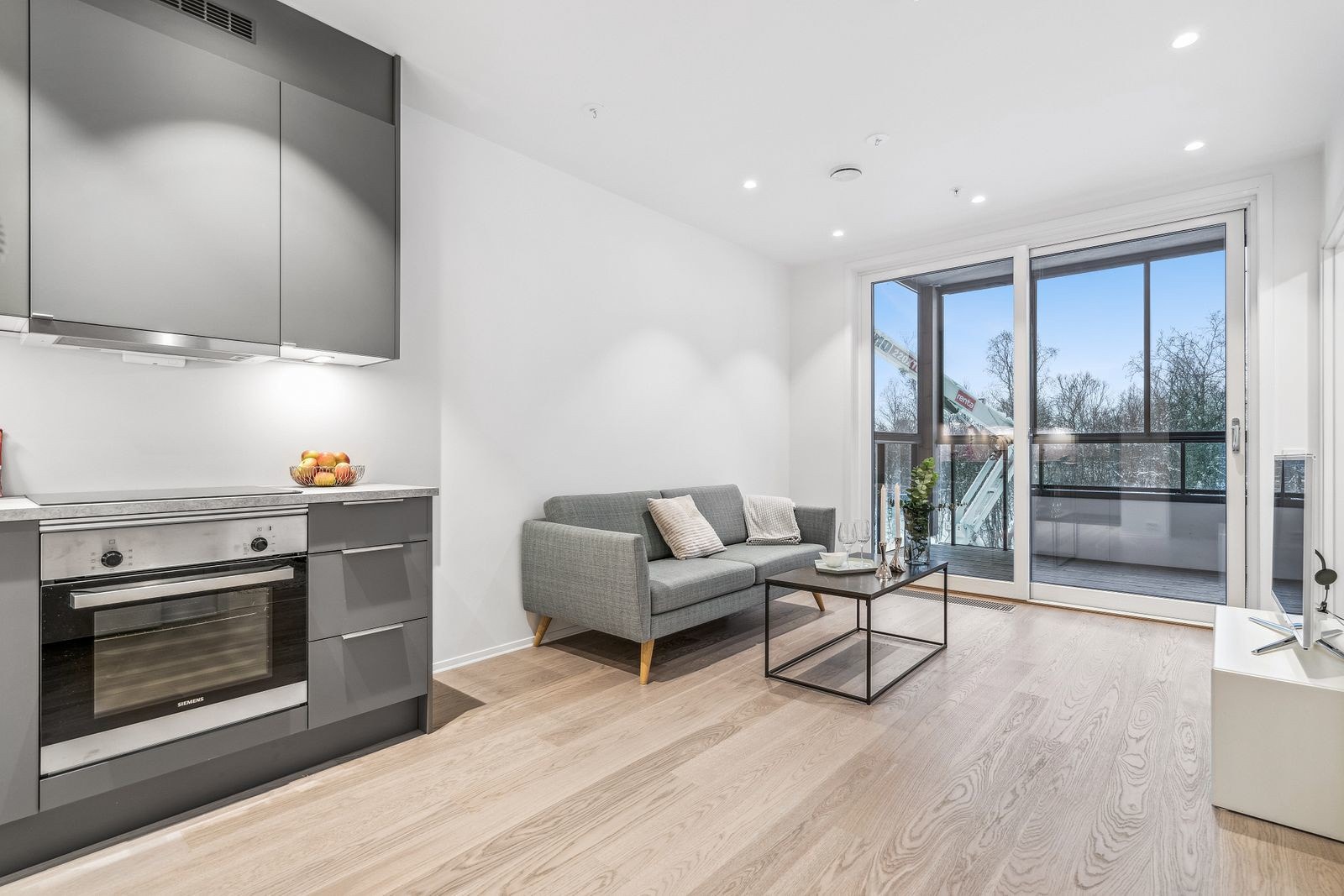 Åpen stue/kjøkken-løsning med utgang til balkong. Gulvet er lagt i lekker parkett.