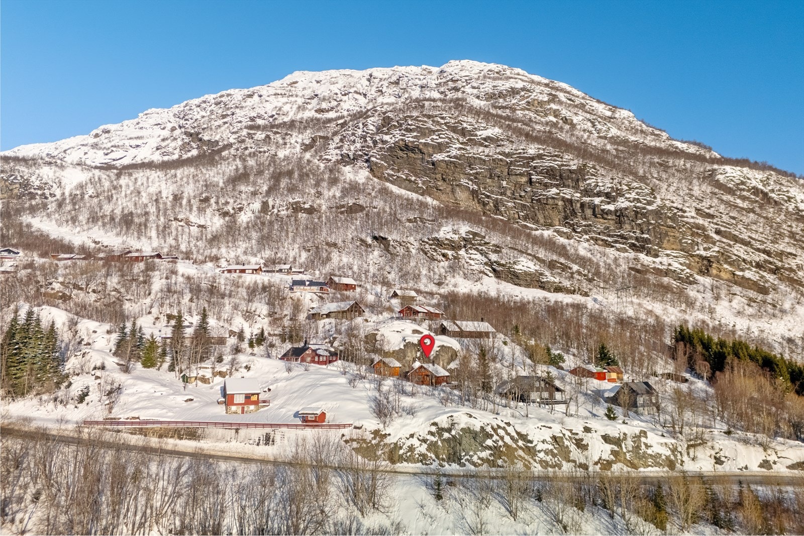 Parkering på felles parkeringsplass for hyttefeltet like nedenfor hytten i avkjørsel fra hovedvei. Gangsti fra parkering til hytten. Galleribilde
