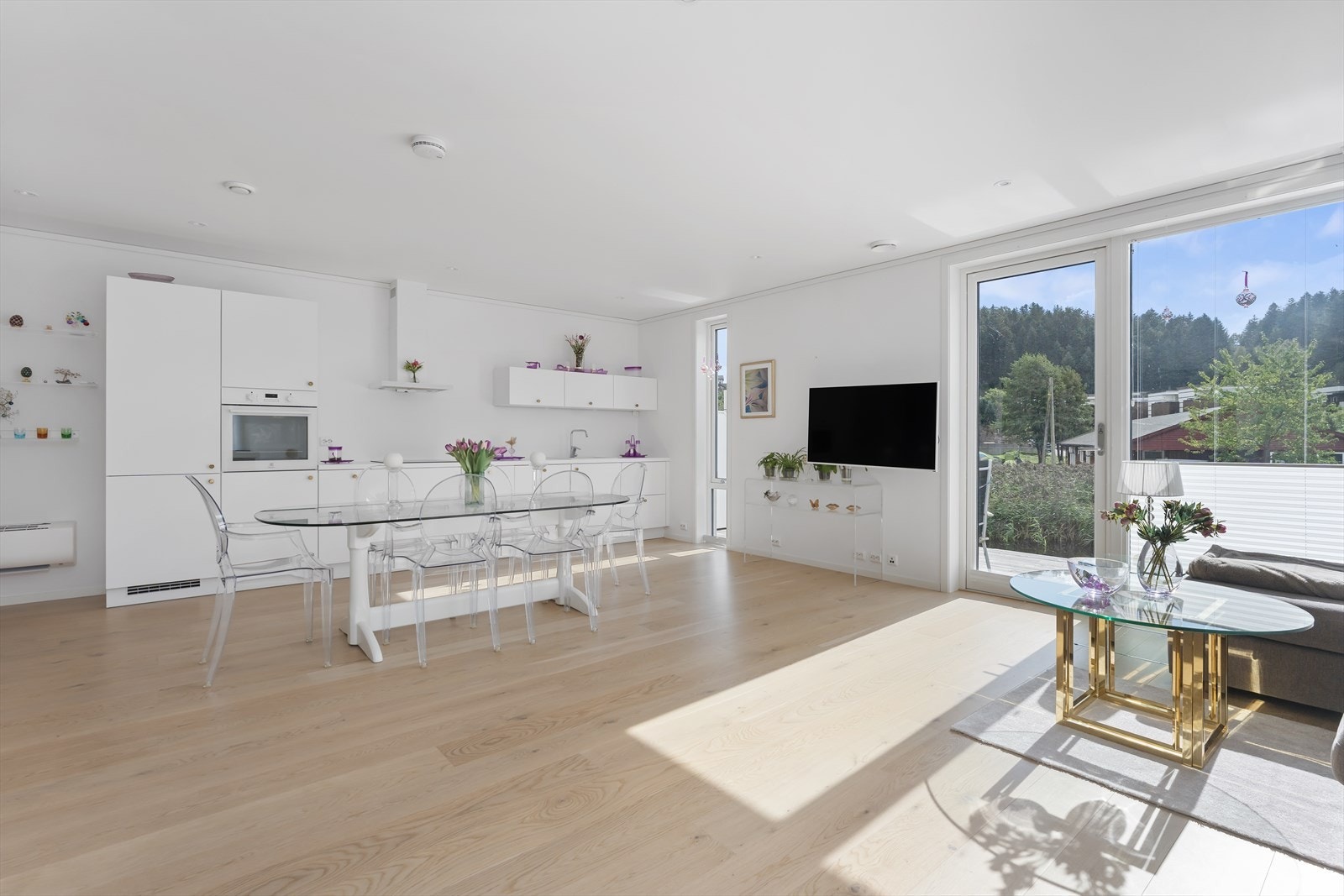 Utsikt og flott naturlig lys fra de store vindusflatene - kjøkkenet er lekkert hvitt med fine arbeidsflater og god plass til oppbevaring Galleribilde