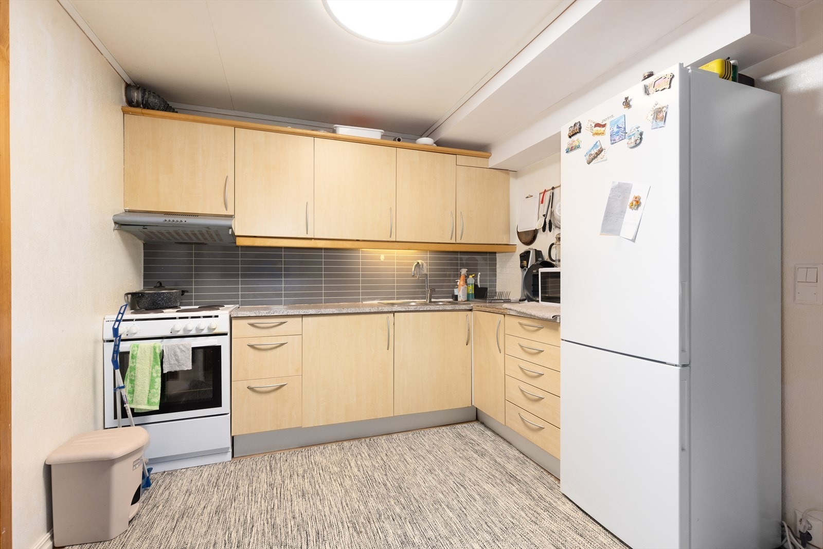 Kjøkkenet har innredning med slette fronter, laminat benkeplate og beskyttelsesplater over kjøkkenbenk. Det er kjøkkenventilator med avtrekk ut og avsatt plass til komfyr og kjøleskap. Galleribilde