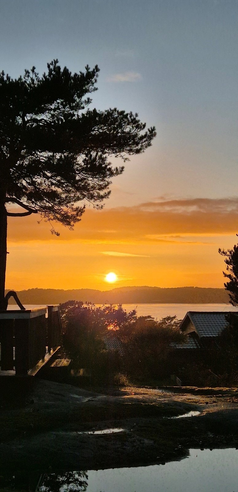 Nydelig solnedgang som glir ned mot horisonten, med glimt av sjøen som speiler dagens siste lys. (Selgers bilde) Galleribilde