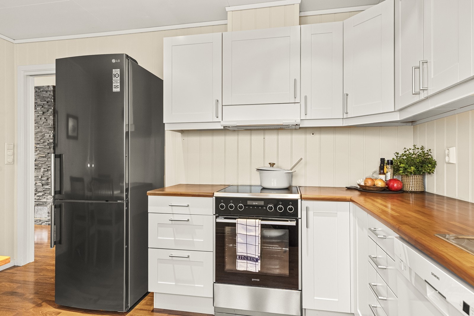 Det er godt med skap- og benkeplass i innredningen. Hvitevarene er frittstående, og over komfyren er det montert kjøkkenventilator med avtrekk ut. Galleribilde