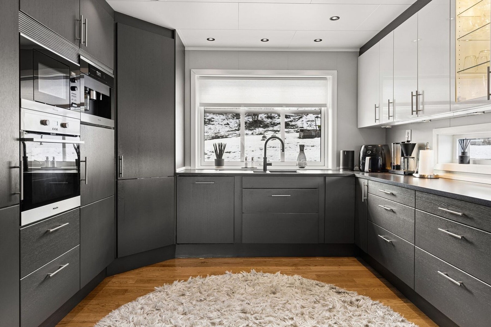 Kjøkkenet har fine og mørke overflater med integrerte hvitvarer som induksjonstopp, ovn, micro og oppvaskmaskin. Galleribilde