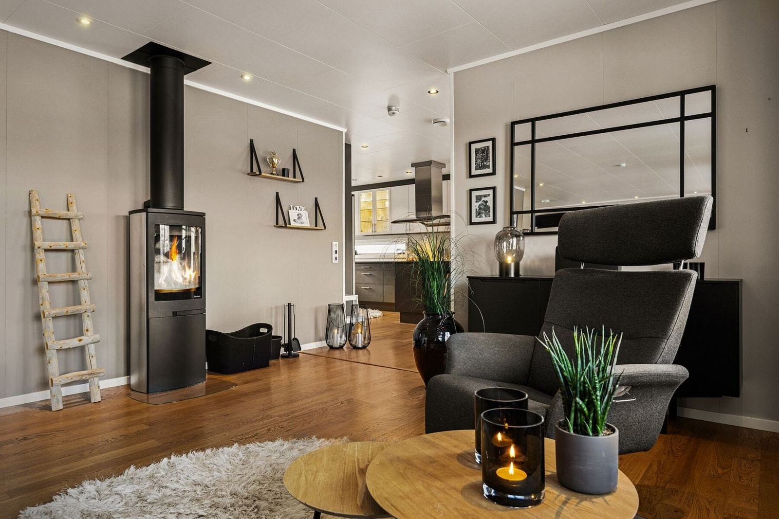 Veggflatene er malt i duse farger. Den moderne vedovnen gir lun varme på kalde vinterdager. Galleribilde