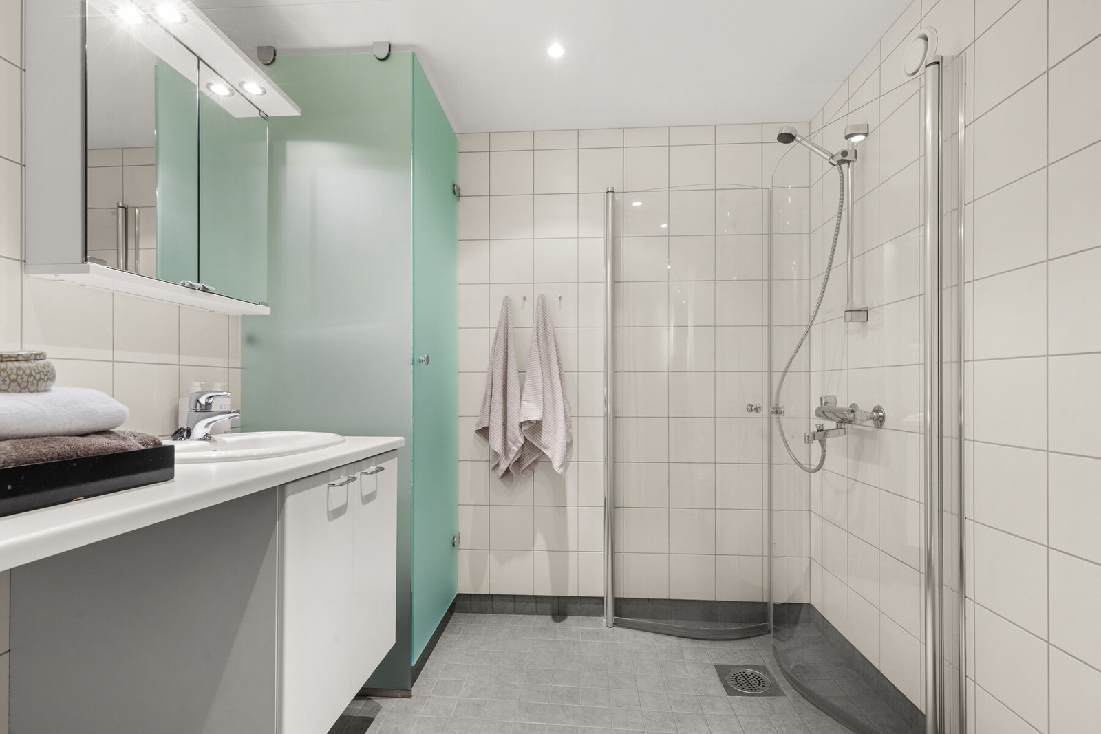 Dusj på gulv med dører i herdet
glass, servant, tørkeskap, veggfestet klosett med innebygget
sisterne og opplegg for vaskemaskin. Galleribilde