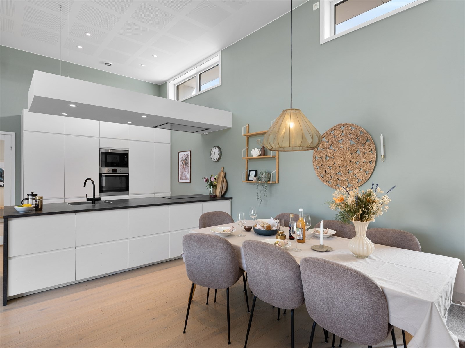 Romslig kjøkken i hvit utførelse ,ed mørk benkeplate med integrerte hvitevarer Galleribilde