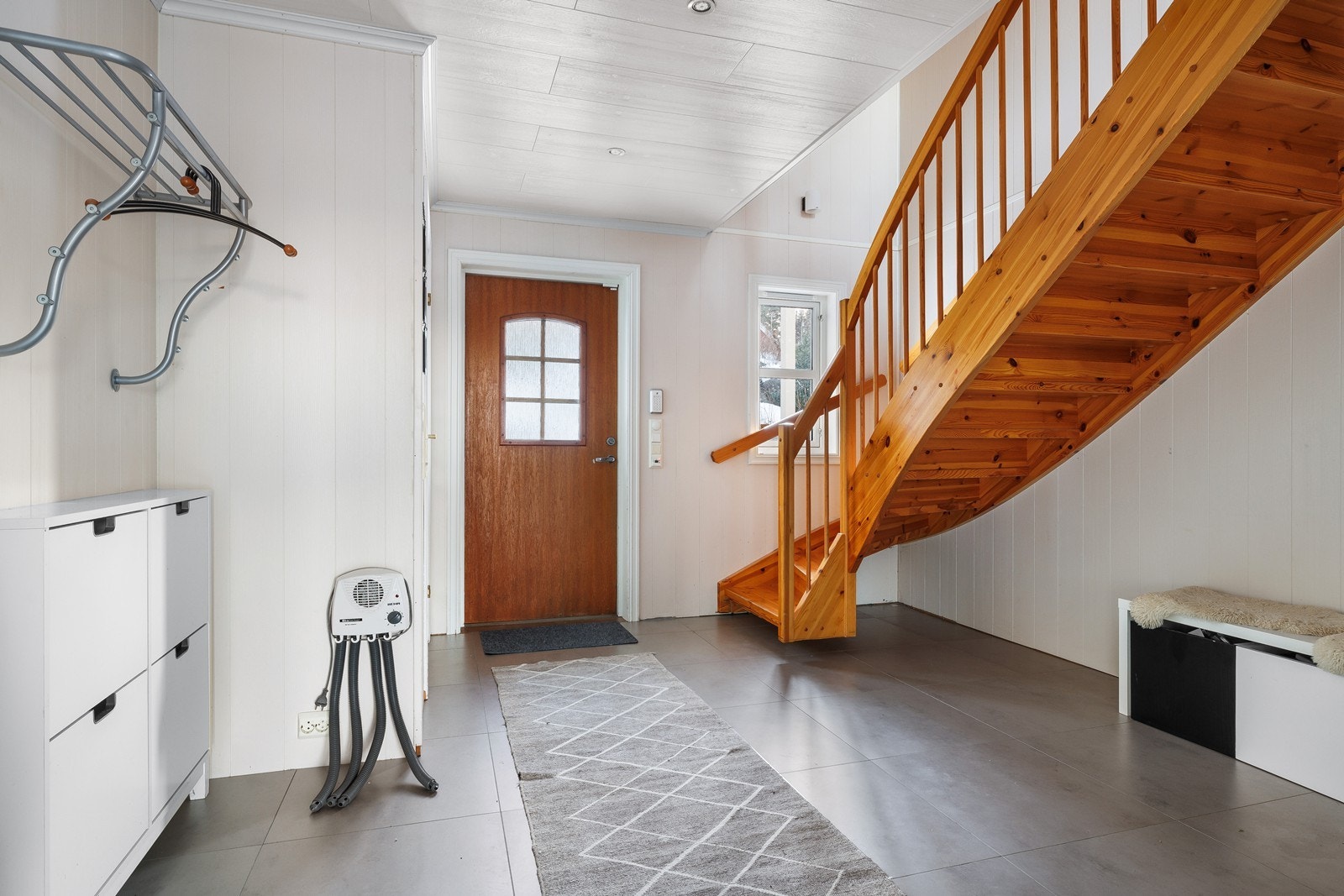 Romslig entre og gang med god plass til yttertøy og sko. Fliser og varmekabler på gulv. Galleribilde