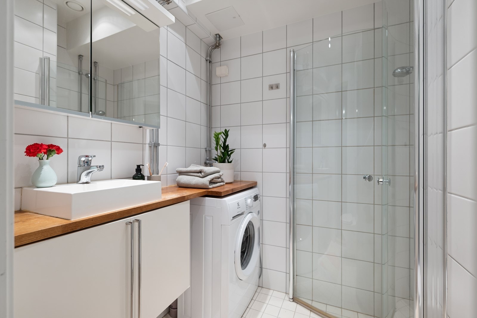 Med et praktisk dusjhjørne, vaskeservant med underskap, overskap med speil, vannklosett og vaskemaskin er badet fullt utstyrt. Galleribilde