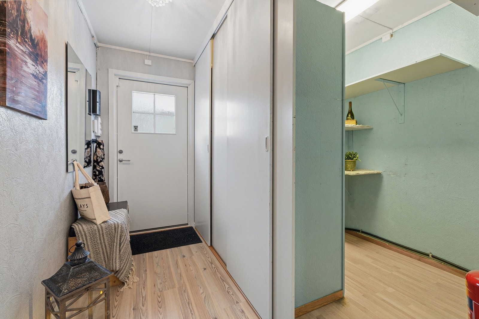 Entréen har gode oppbevaringsmuligheter med skyvedørsgarderobe. Rommet er delt av og det er etablert hyllesystem i deler av entrèn som fungerer som bod Galleribilde