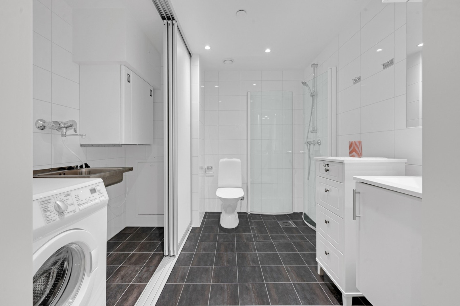 Praktisk med egen vaskedel med skyvedørsgarderobe på bad. Galleribilde