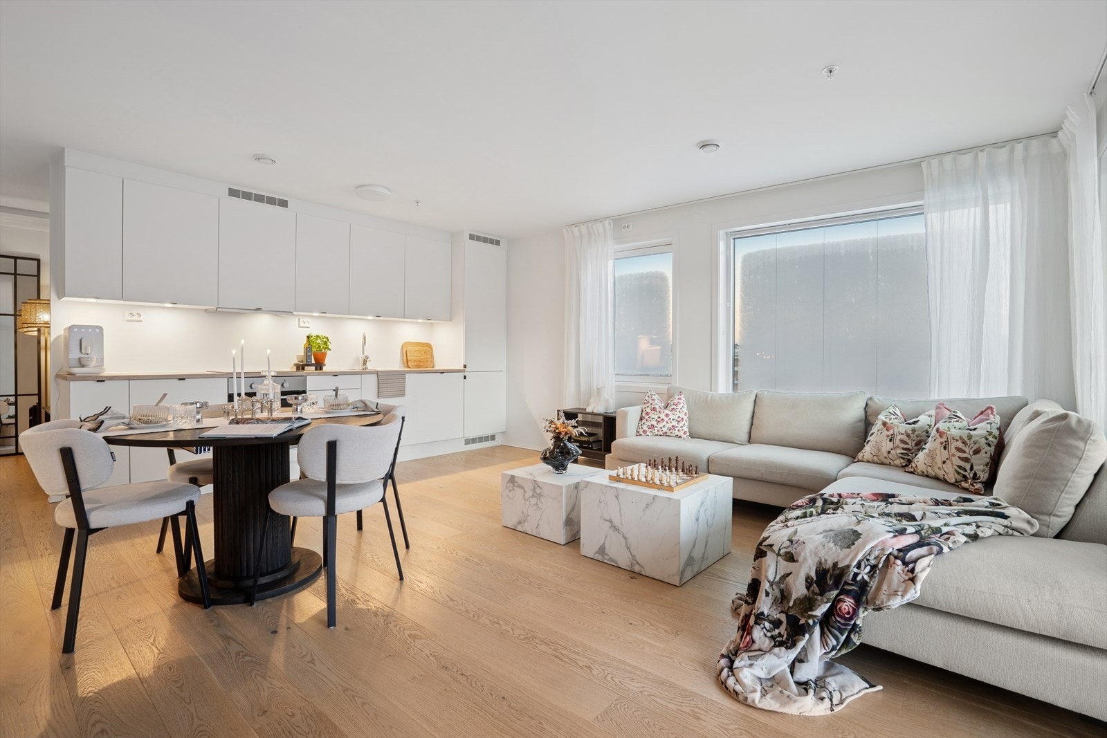 Et innbydende allrom med lyse overflater og gjennomgående en-stavs parkettgulv. Galleribilde