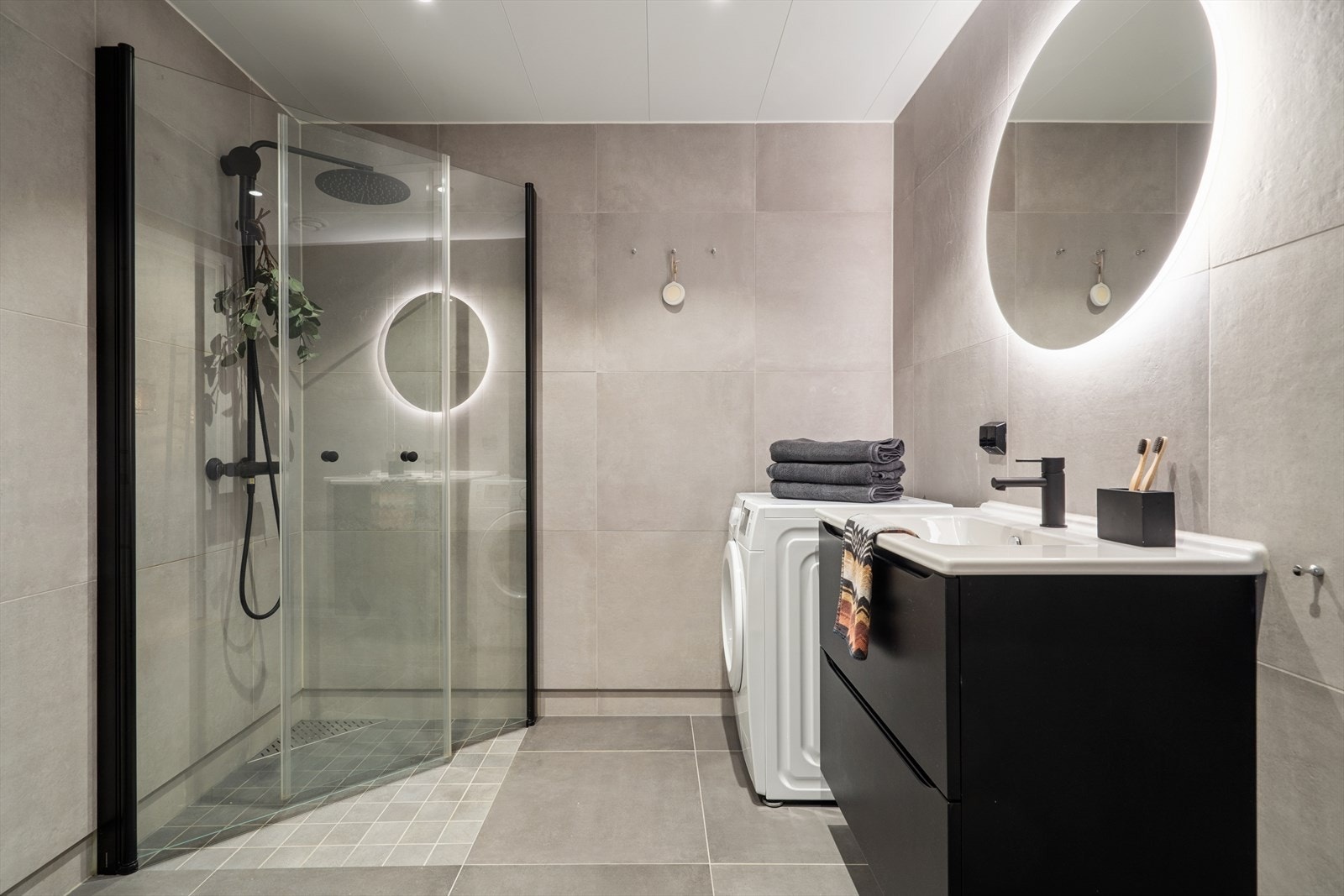 Badet er fra byggeåret og fungerer som kombinert bad og vaskerom. Rommet har fliser på gulv og vegger, med sparklet og malt gips i himlingen. Galleribilde