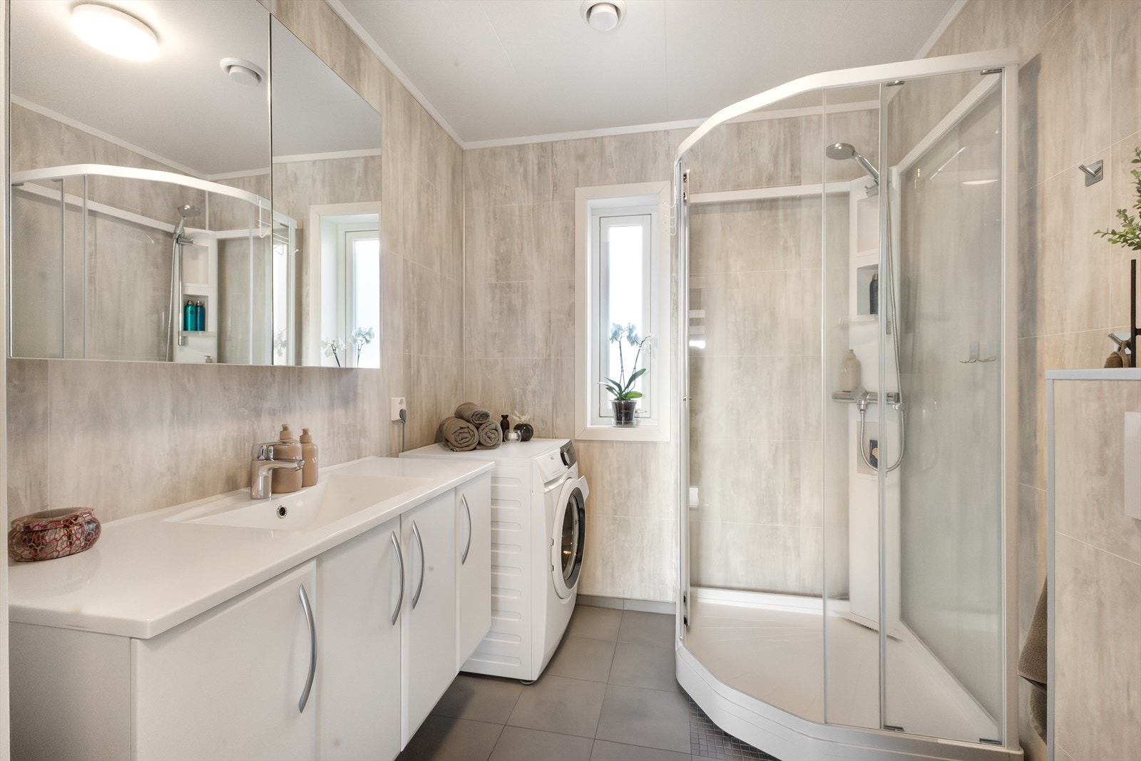 Badet i 2.etg er romslig og har opplegg for vaskemaskin og tørketrommel. Selvsagt flislagt gulv med varmekabler. Stort speilskap og romslig innredning under vask. Galleribilde