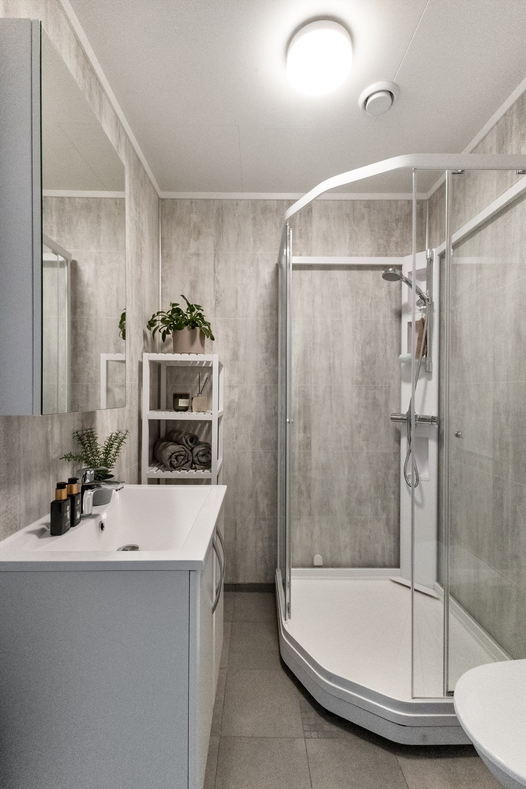 Badet i 1.etg har flislagt gulv med varme, romslig innredning med bla. speilskap og stort dusjkabinett. Galleribilde