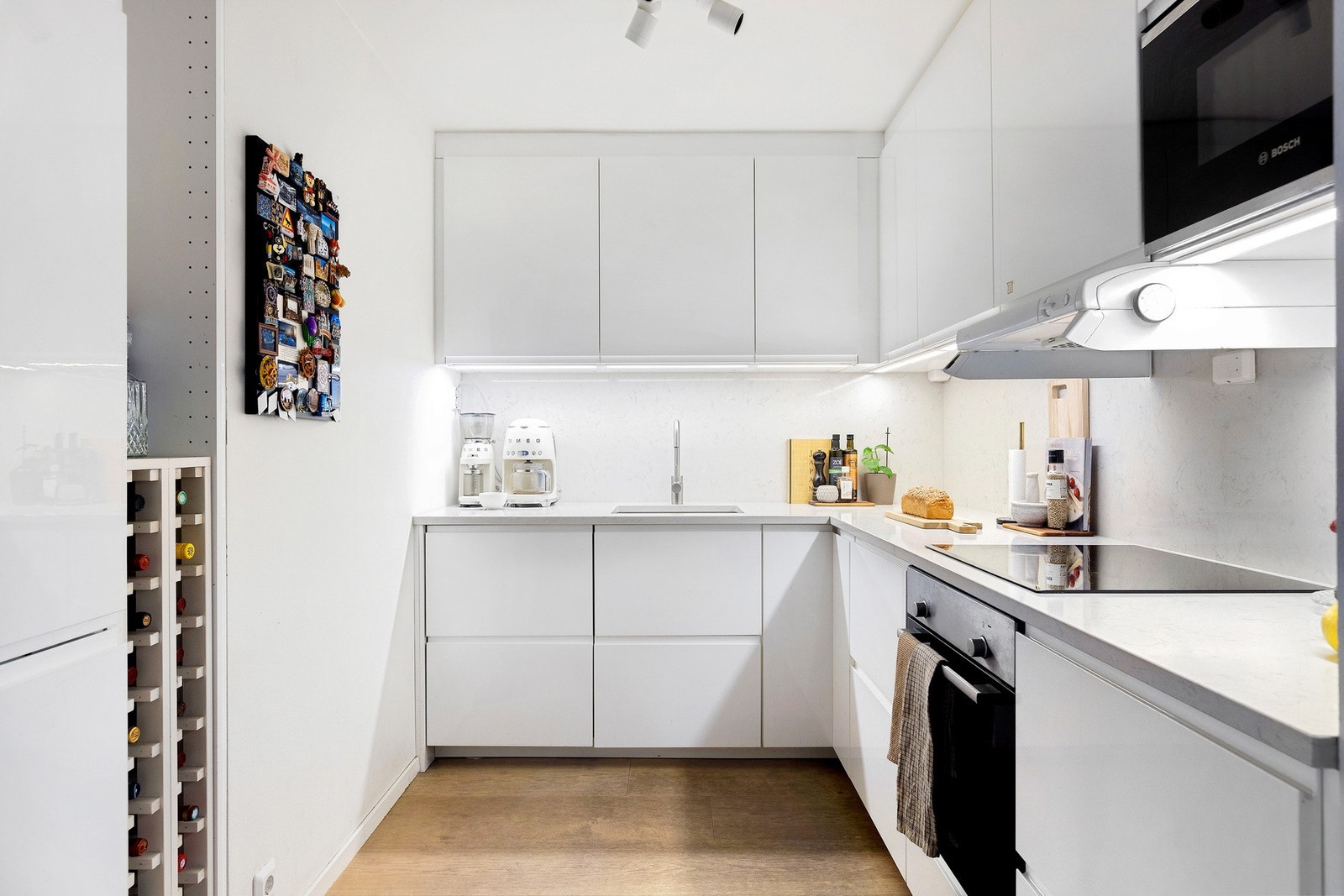 Benkeplate av stein med nedsenket oppvaskkum og ett-greps armatur.
Induksjonstopp og integrert komfyr, oppvaskmaskin og kjøleskap med frysede Galleribilde