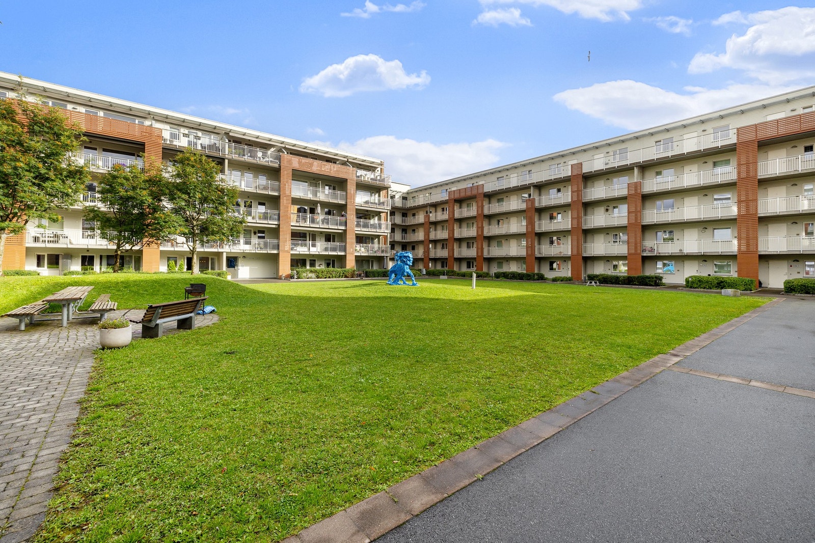 Pent opparbeidet gårdsrom med grill, beplantning, sittegrupper og asfalterte internveier. Galleribilde