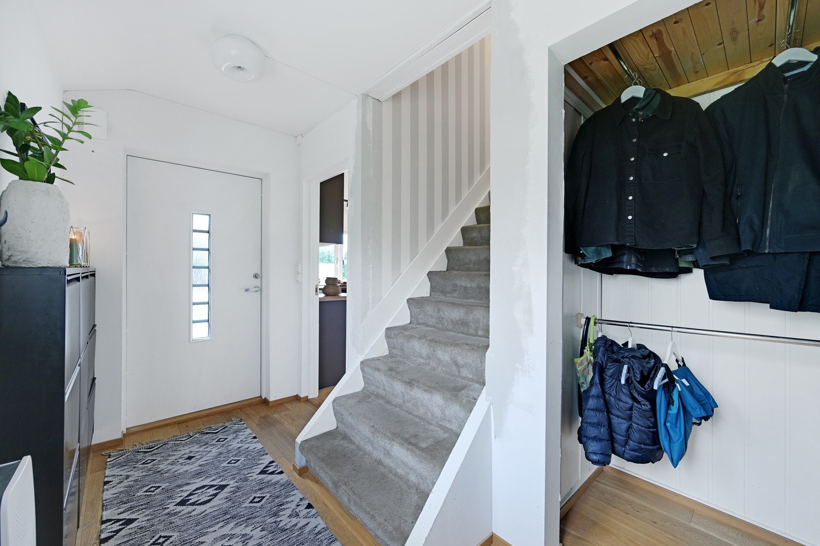 Romslig entrè i hovedetasjen med plass til å sette fra seg sko og henge opp yttertøy Galleribilde