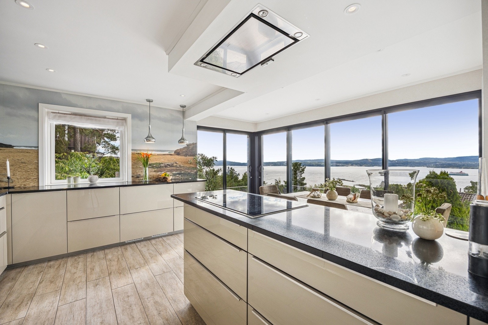 Innredningen består av en moderne kjøkkenløsning med glatte, elegante fronter og en solid kompositt benkeplate som kombinerer holdbarhet med et stilrent uttrykk. Galleribilde