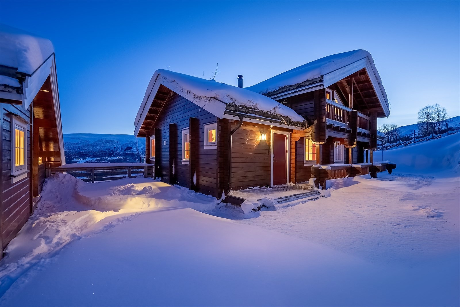 Hytta ble oppført i 2008 - Inngangsparti med terrasse som strekker seg rundt tre sider av bygget Galleribilde