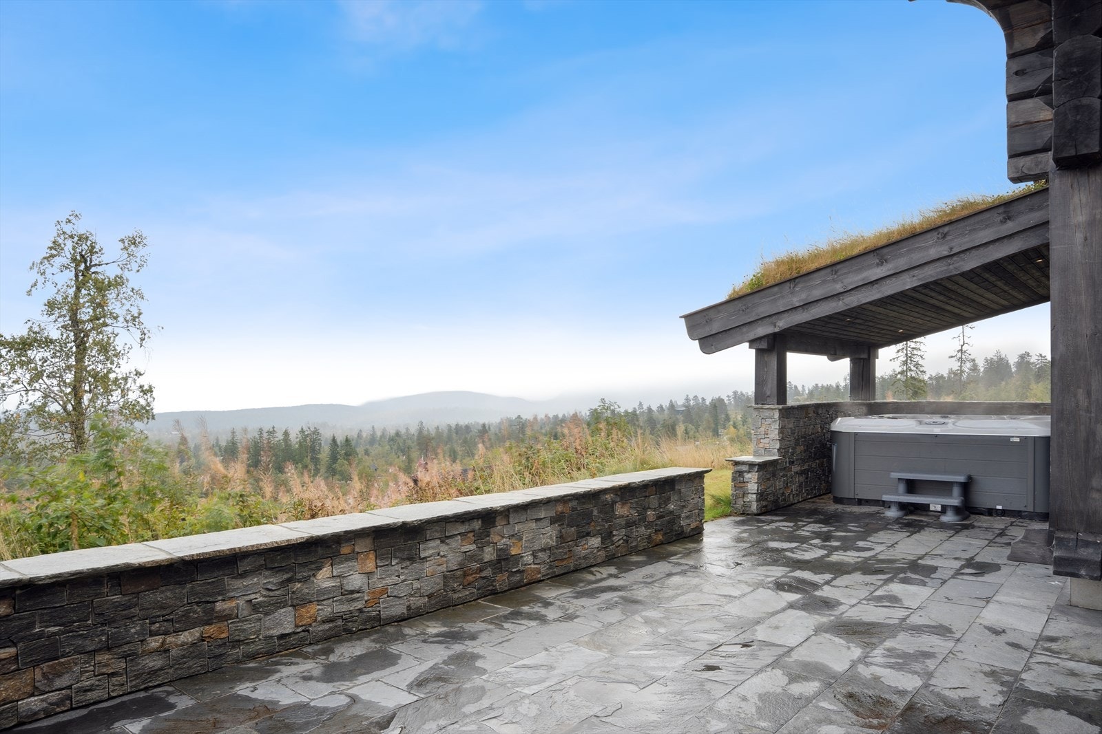 Terrassen er gjerdet inn med skifer mur og har tilgang til en overbygget jacuzzi med nydelig utsikt. Galleribilde
