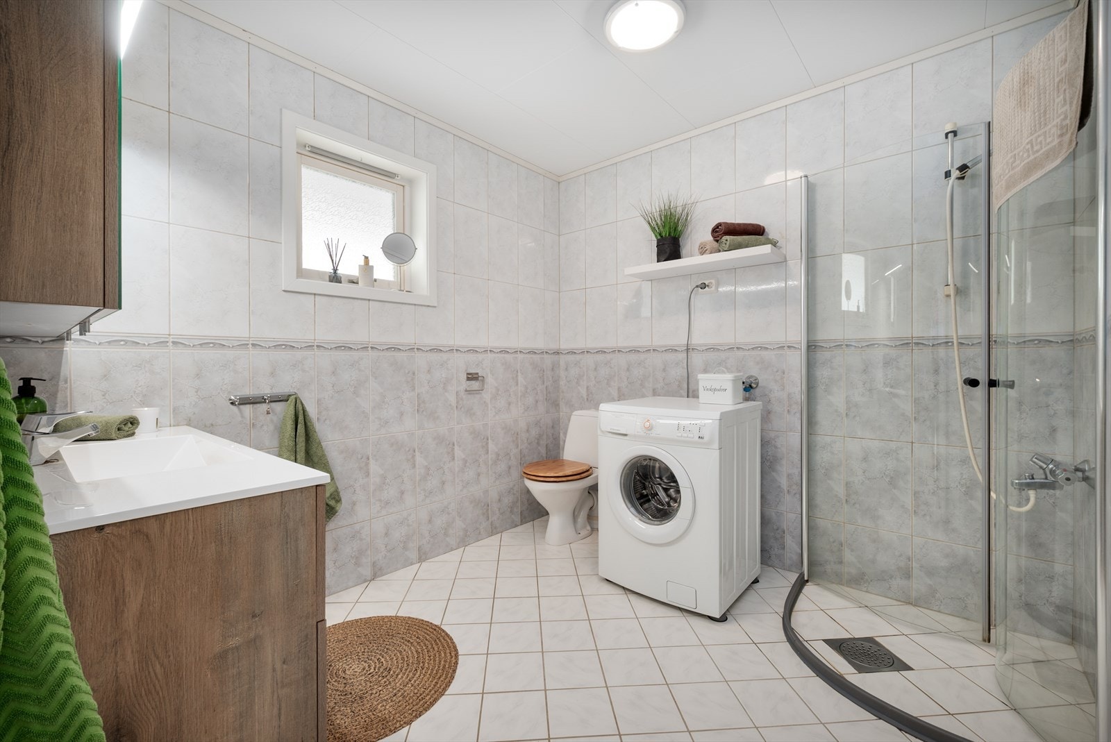 Innredning med servantskap med heldekkende servant, speilskap, toalett, innsvingbare dusjdører og opplegg for vaskemaskin. Galleribilde