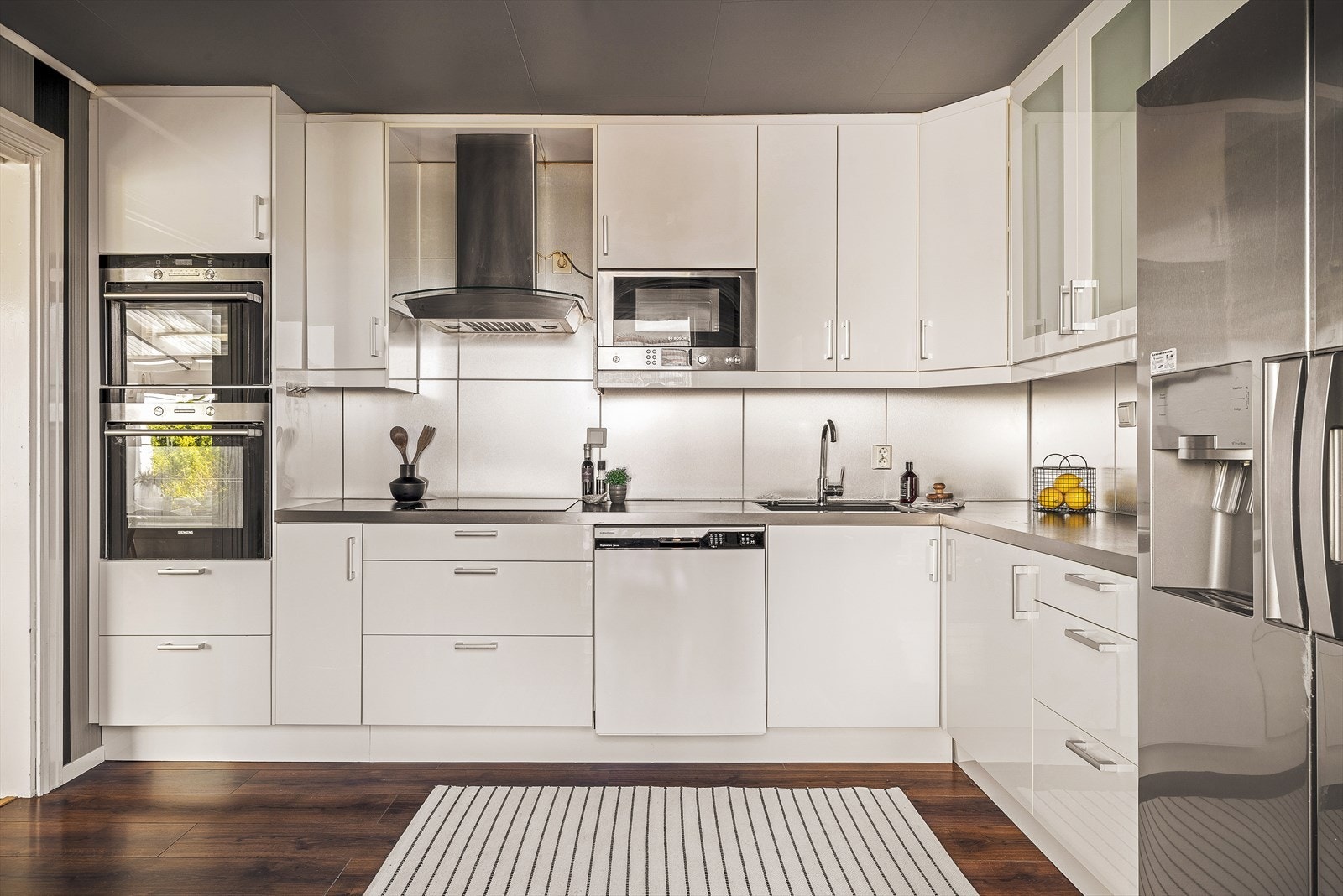 Lekkert kjøkken med integrert induksjonsplatetopp, stekeovn, integrert mikrobølgeovn og opplegg for oppvaskmaskin. Galleribilde