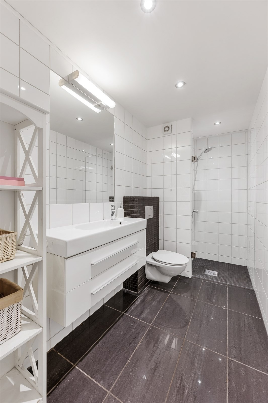 Lekkert, flislagt bad med servant i innredning, romslig dusjsone med glassdør og vegghengt toalett Galleribilde