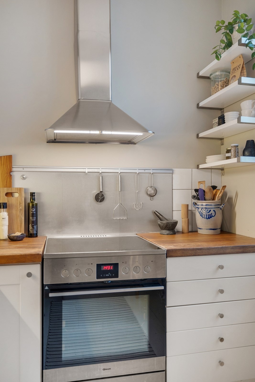 Videre er kjøkkenet innredet med heltre benkeplate, nedsenket oppvaskkum med ett-greps armatur, fliser over kjøkkenbenk og vegghengt kjøkkenventilator med kullfilter. Galleribilde