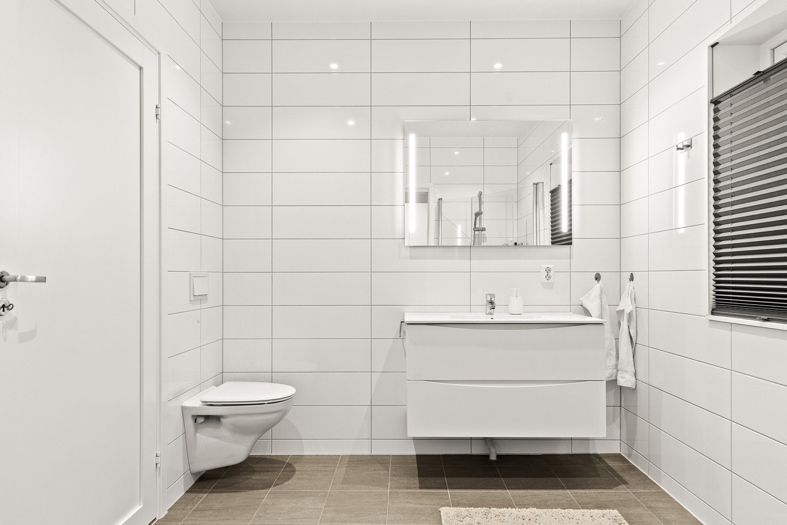 Slett baderomsinnredning med skuffer og enkel servant og innfelte downlights i himlingen Galleribilde