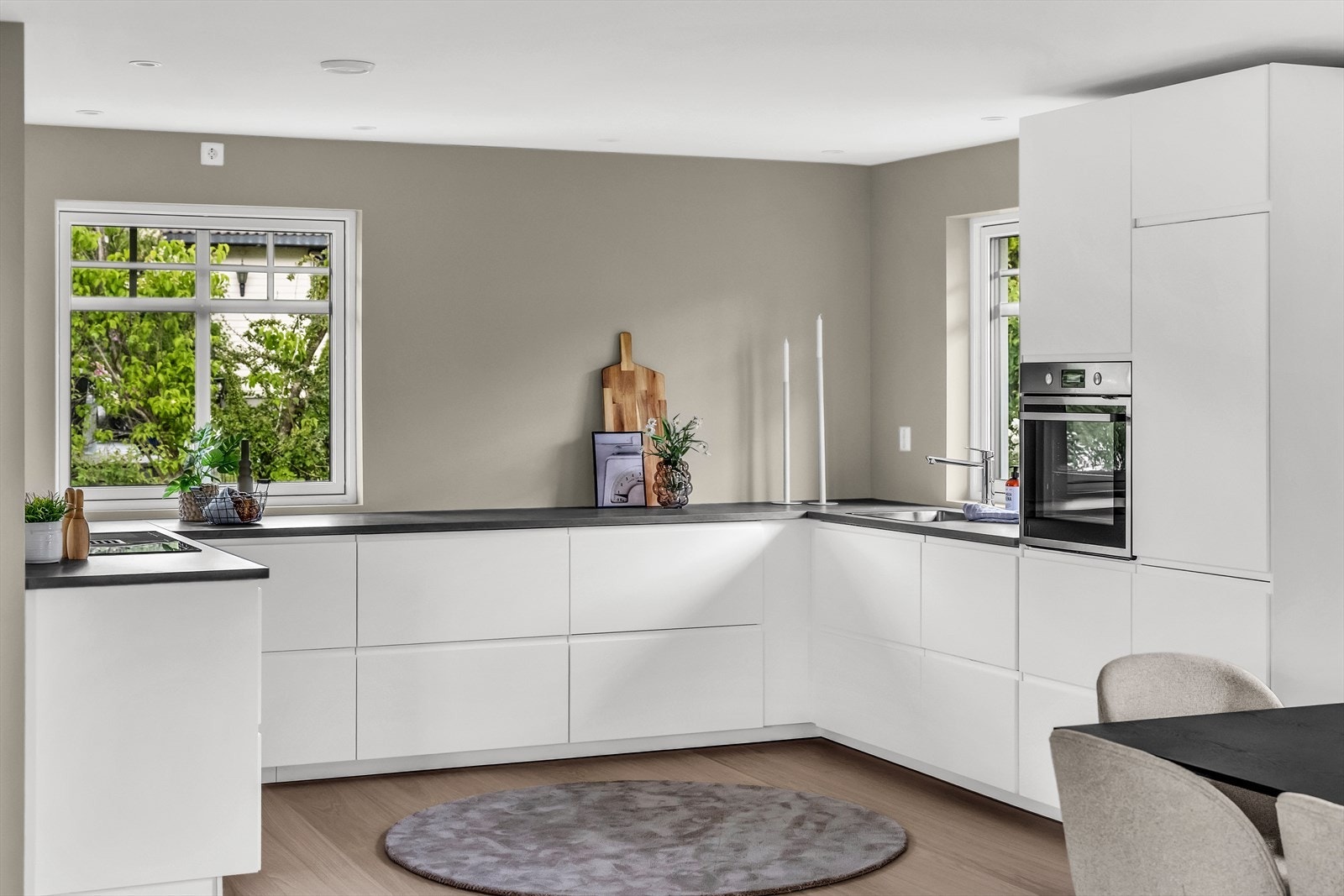 Stort og stilrent kjøkken med åpen løsning mot stuen og med rikelig lys inn via store vinduer Galleribilde