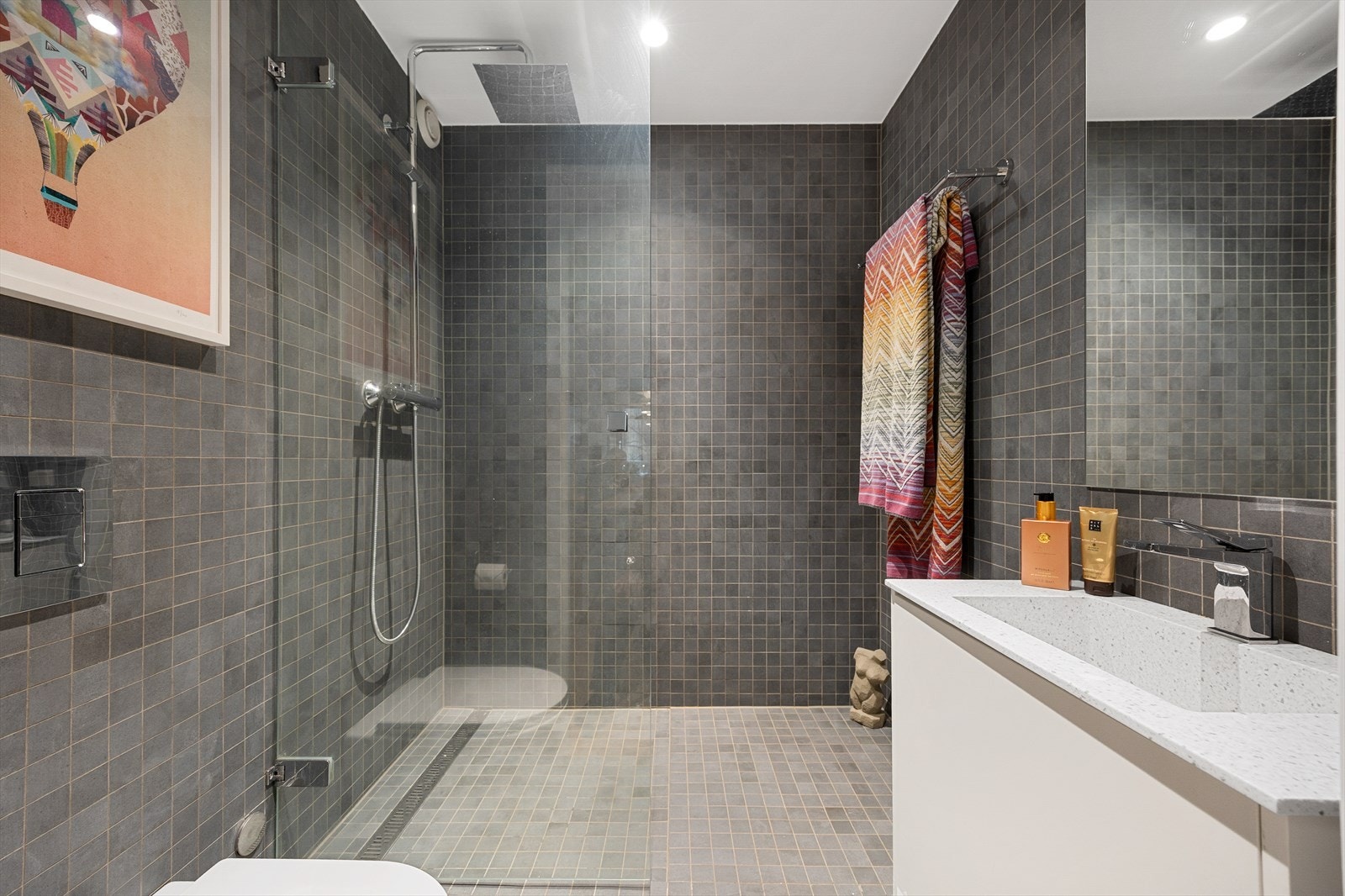 Leilighetens andre bad, også fra 2020, har dusjhjørne med glassdør og slukrenne. Galleribilde