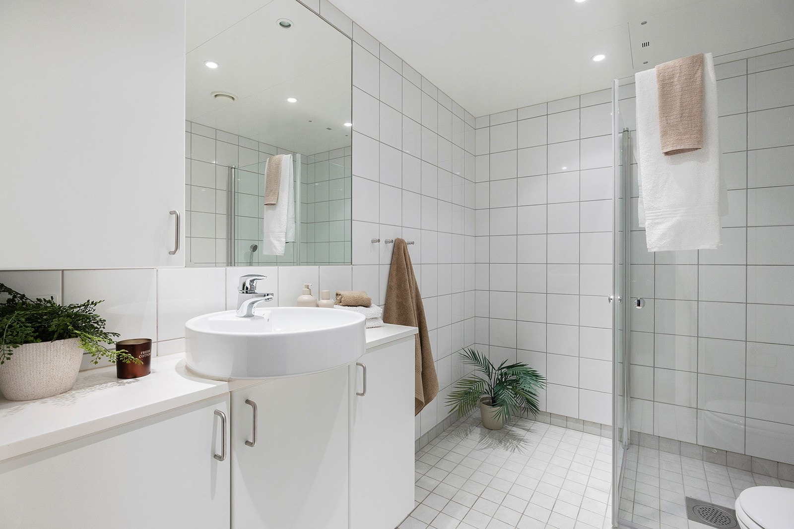 Lyst flislagt bad med varme i gulv og downlights i himling. Galleribilde