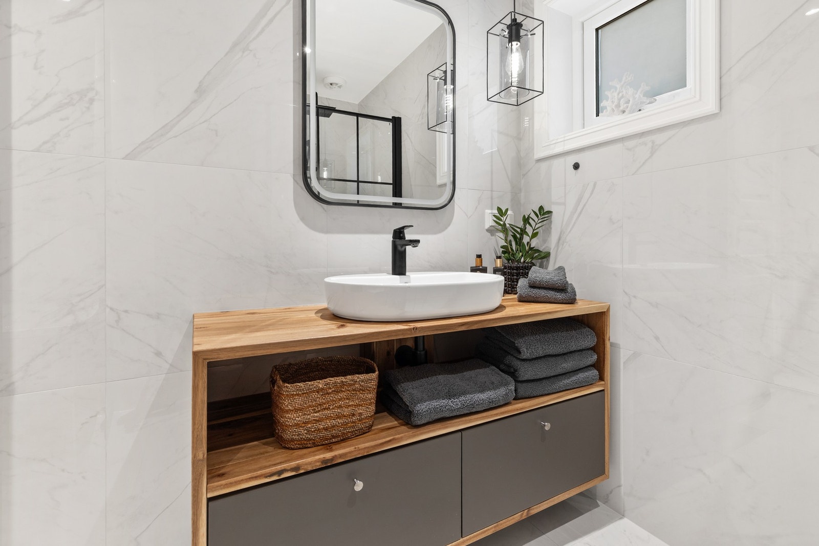 Badet er innredet med servantinnredning med bolleservant, vegghengt toalett og dusjhjørne med glassvegger og regndusj Galleribilde