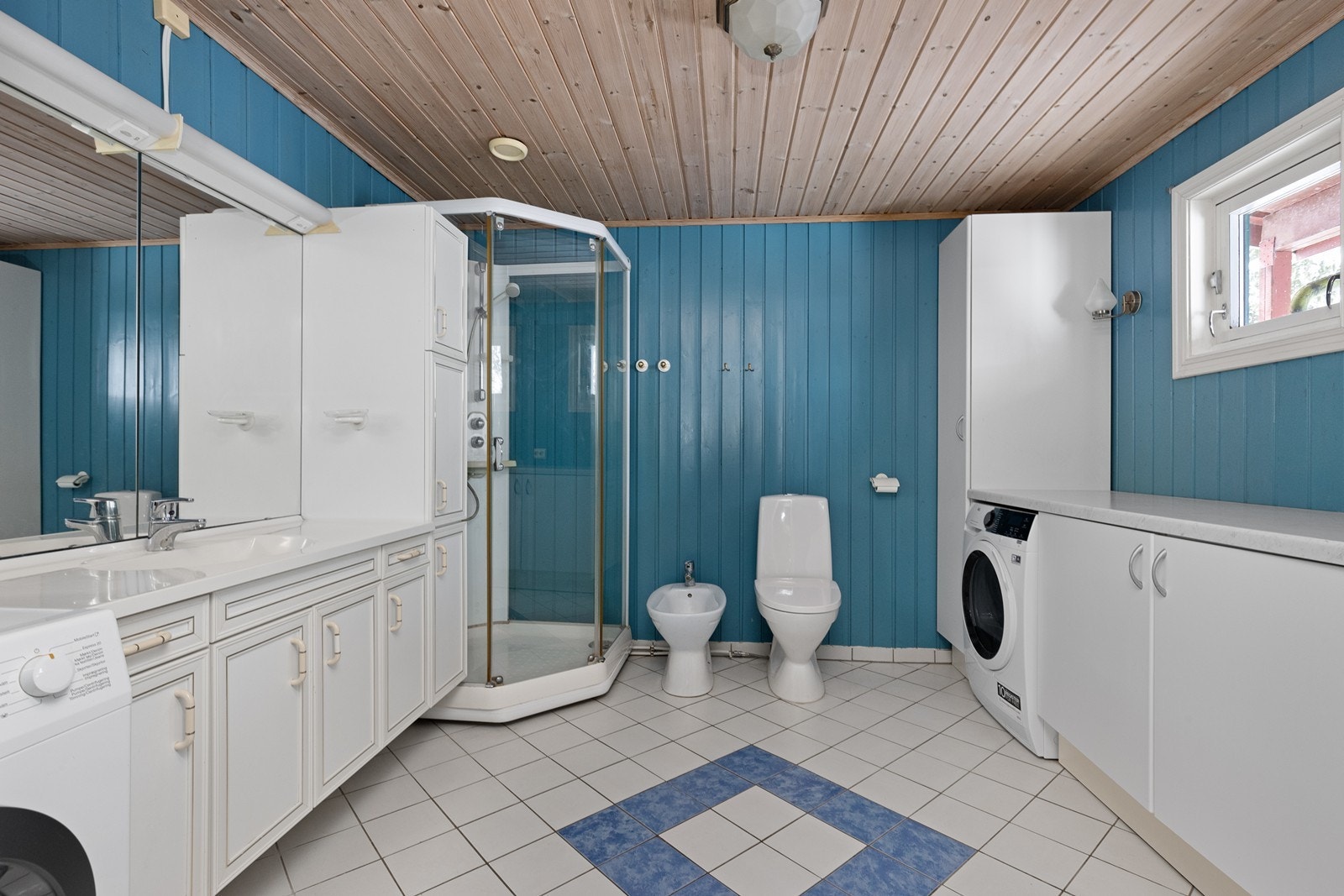 Romslig, flislagt bad i hytta med dusj, toalett og opplegg for vaskemaskin Galleribilde