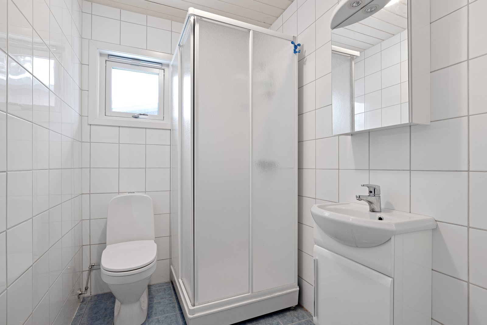 Helfliset bad i leiligheten, utstyrt med dusjkabinett, toalett og servant Galleribilde