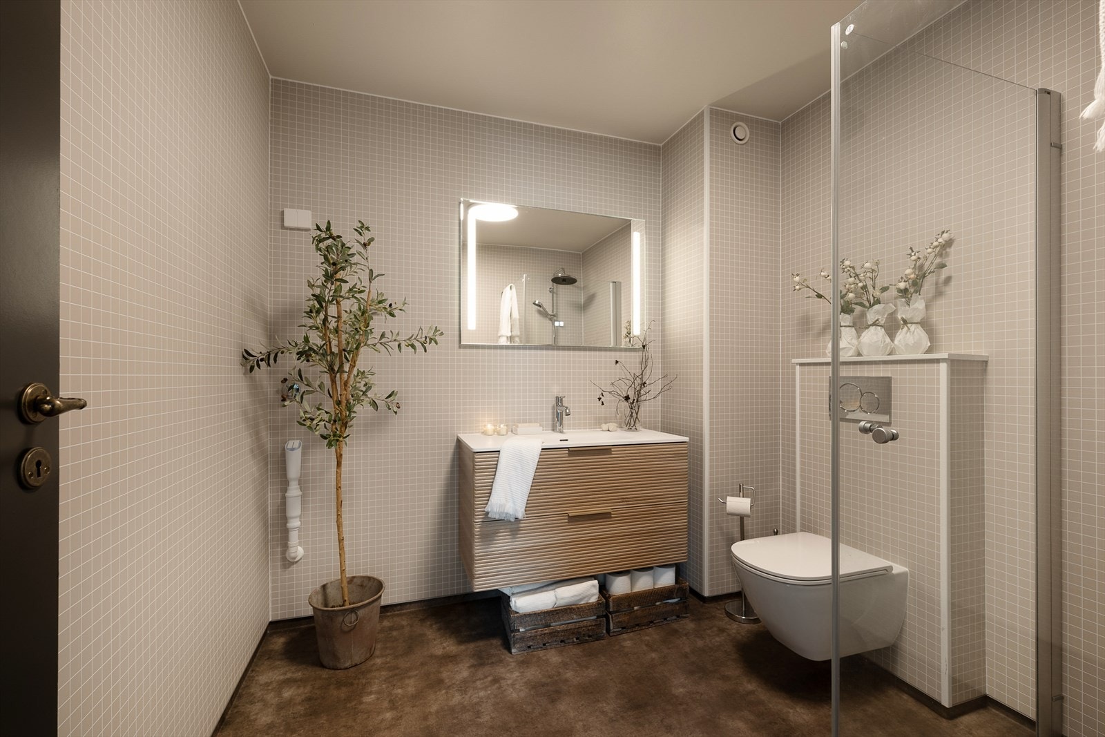 Stilig og nyrenovert baderom har dusjhjørne med glassdører, servant i innredning, vegghengt WC samt opplegg for vaskemaskin. Galleribilde