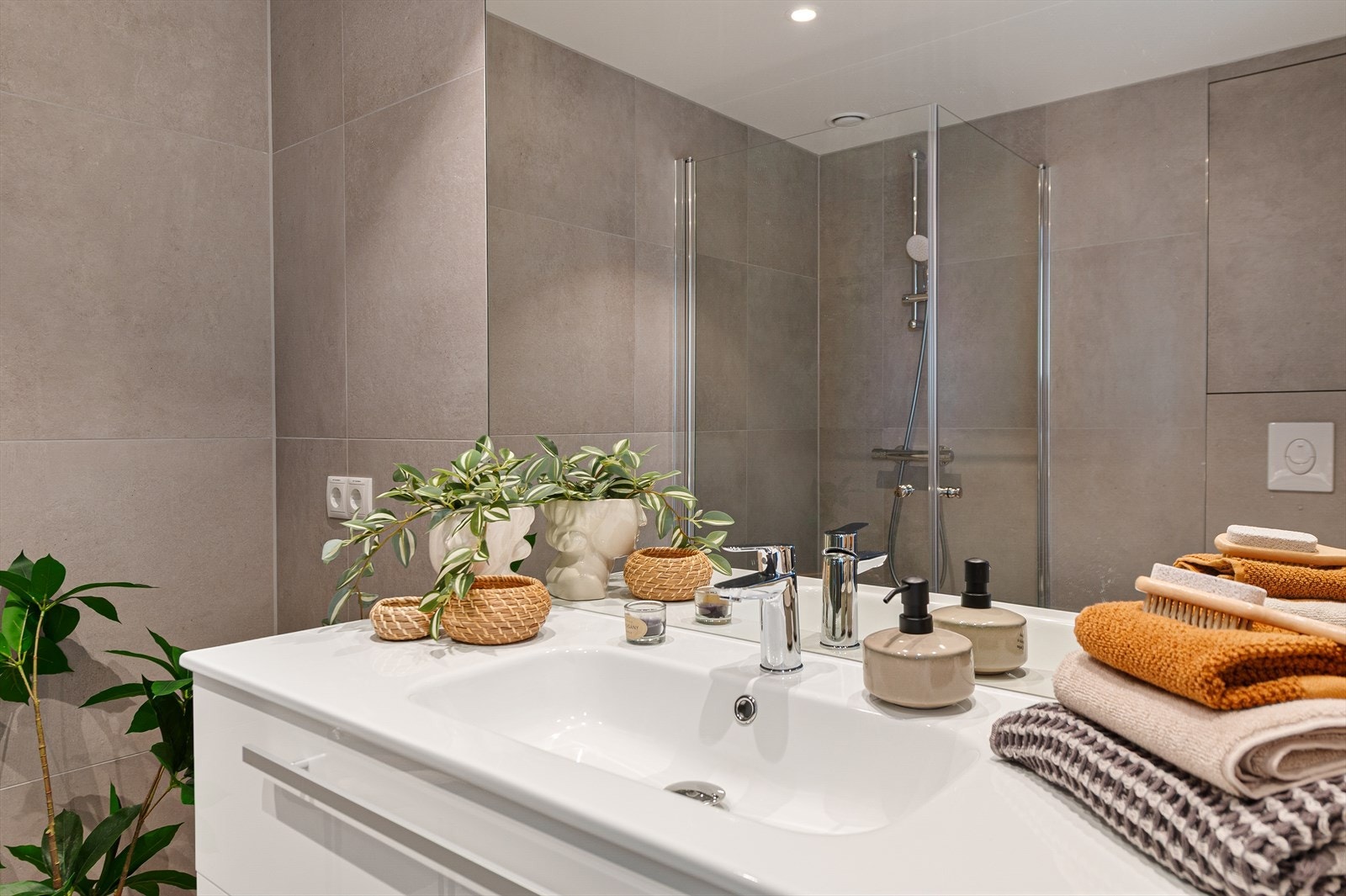 Badet er innredet med dusjhjørne, helservant på skuffeseksjon, speil og vegghengt toalett. Galleribilde