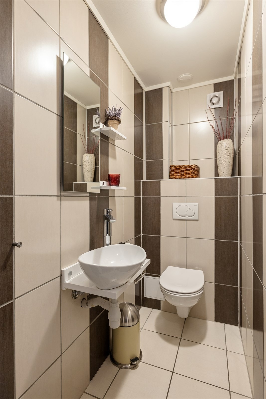 Det separate toalettrommet er holdt i samme utførelse som boligens bad med fliser på både gulv og vegger, samt malte plater i himlingen. Det er innredet med en servant, speil og vegghengt toalett. Galleribilde