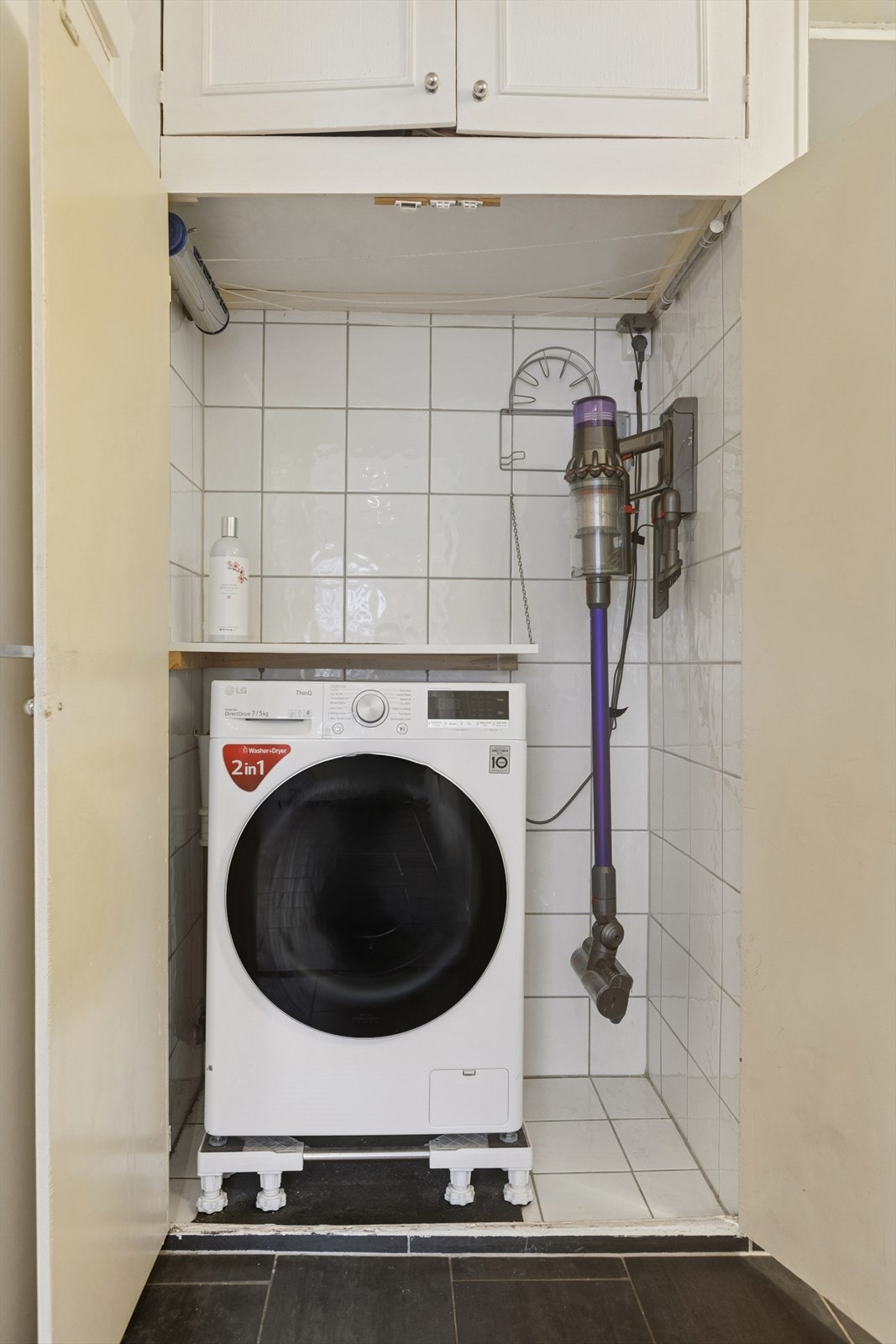 Skap i entré med opplegg for vaskemaskin. Her er det fliser på vegger og gulv. Galleribilde