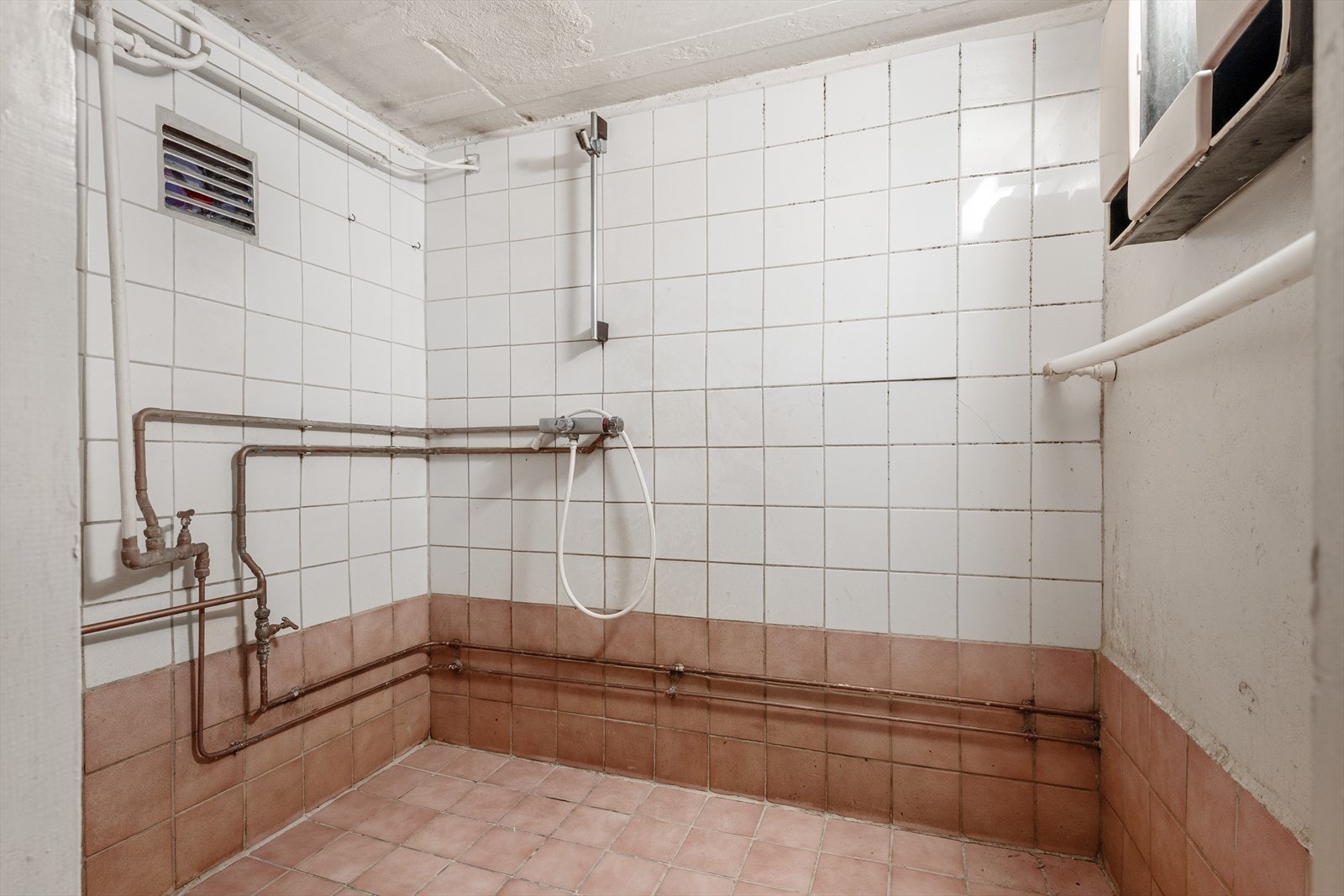 Flislagt sanitærrom med dusj på vegg. Galleribilde